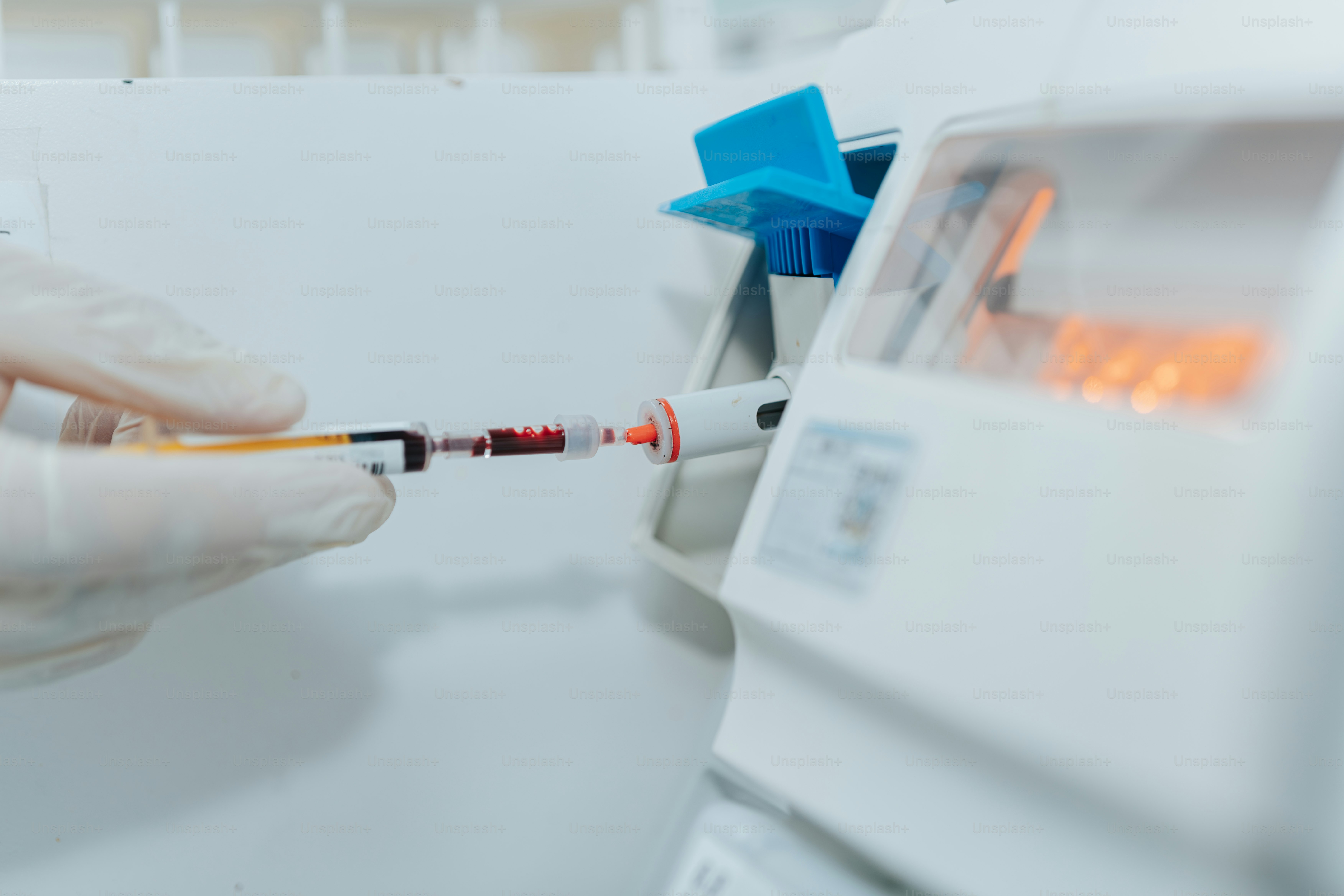 A person in white gloves is holding a tube