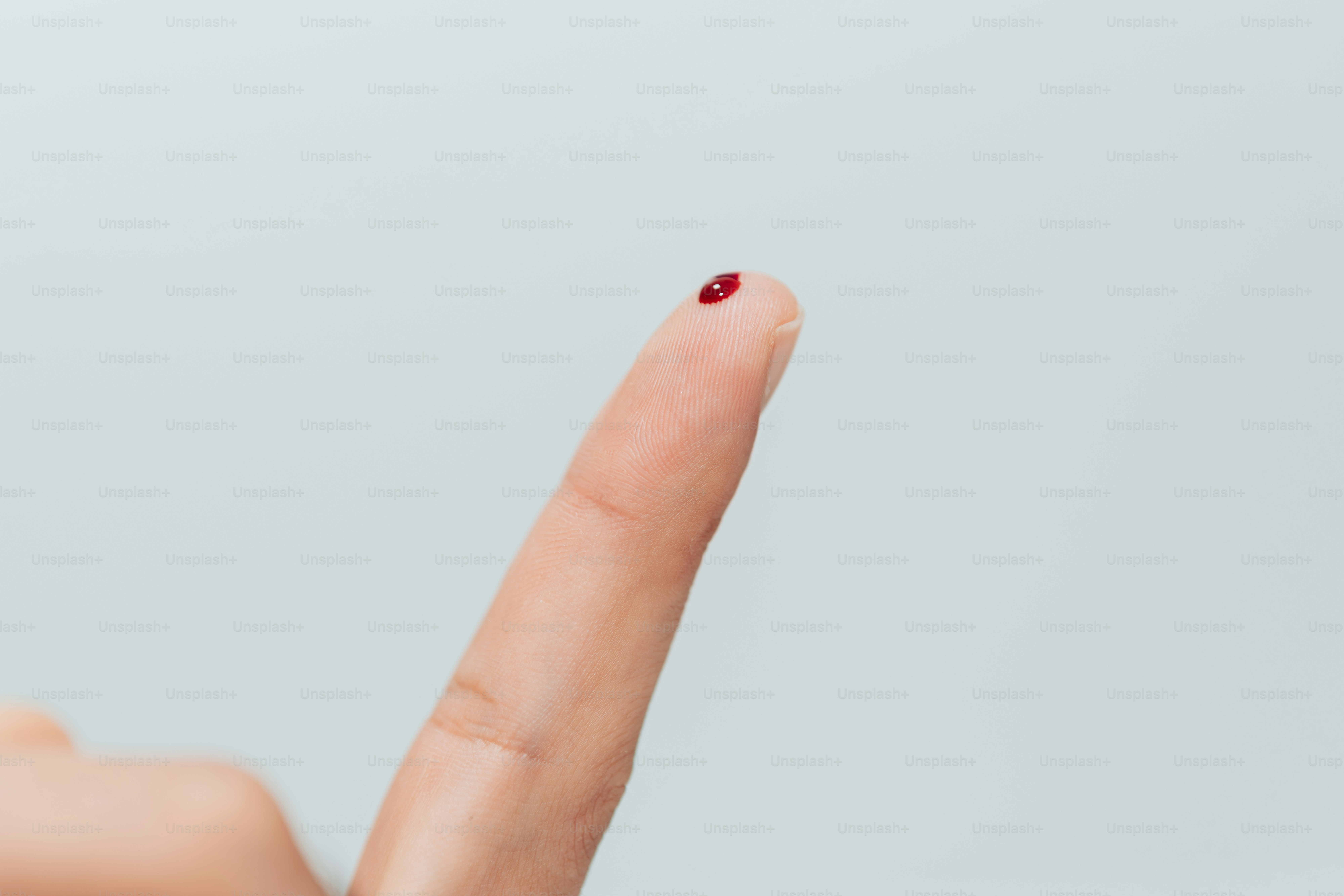 A woman's hand with a red nail polish pointing up