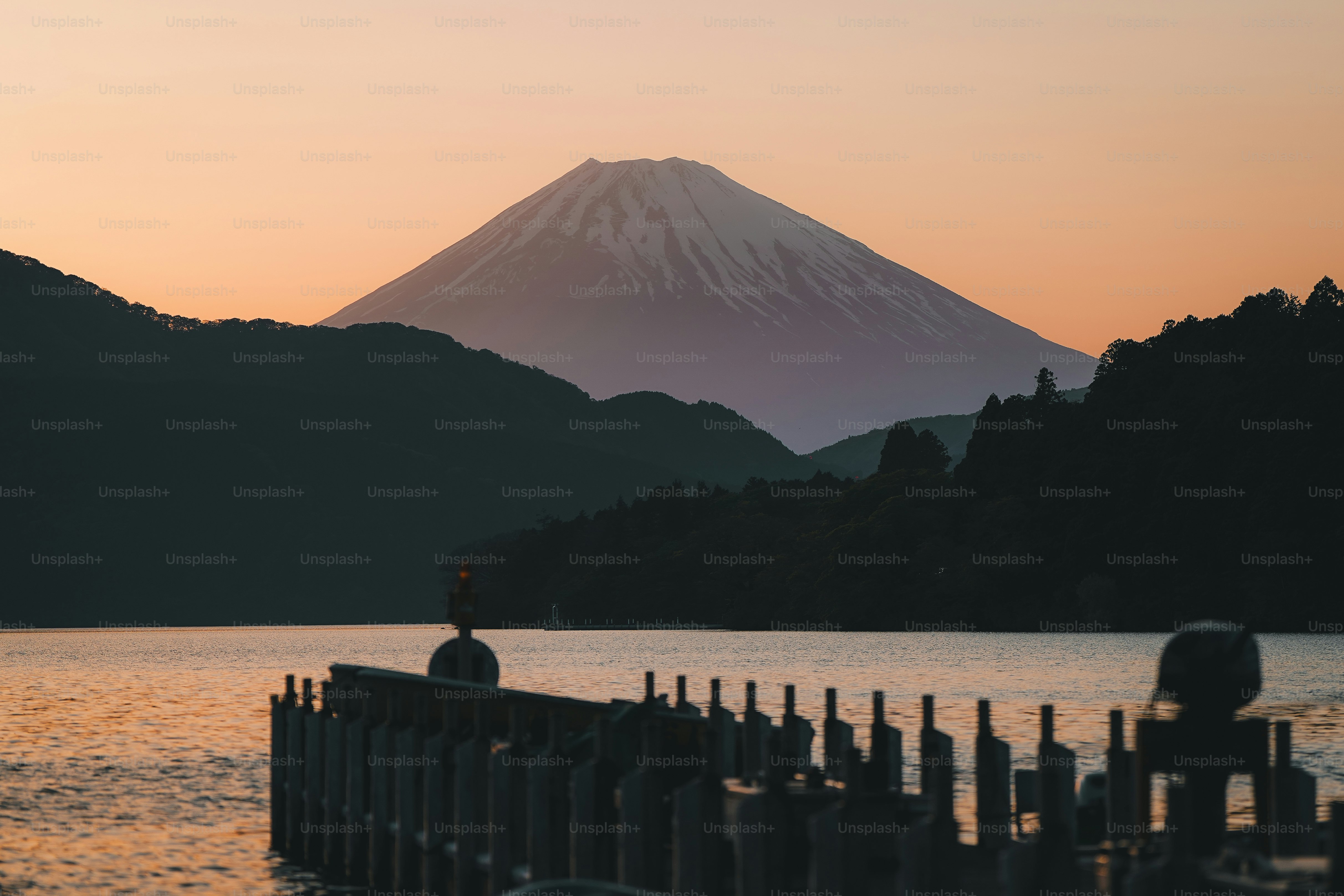 A person standing on a dock in front of a mountain