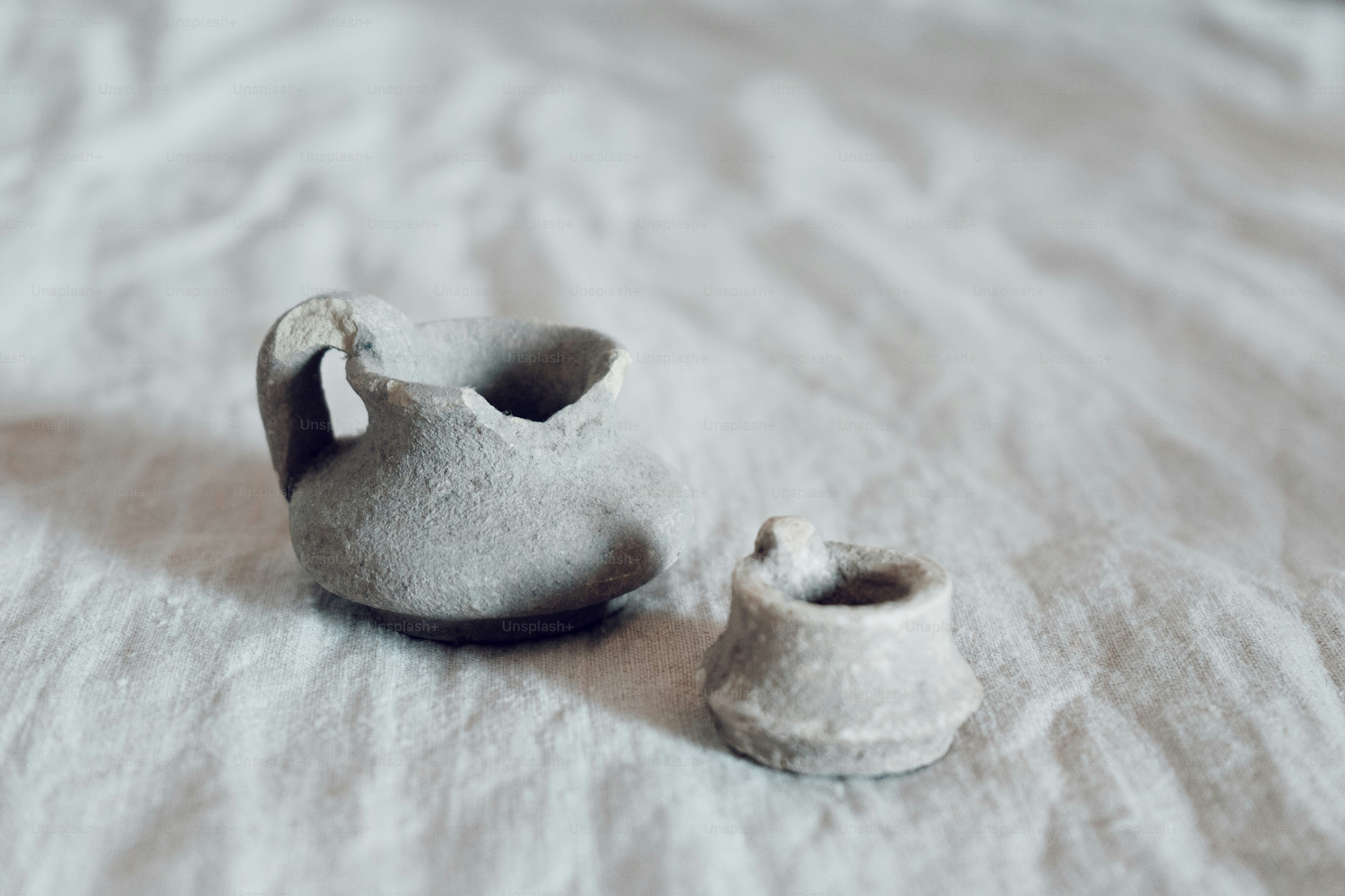 Um pequeno vaso branco sentado em cima de uma cama