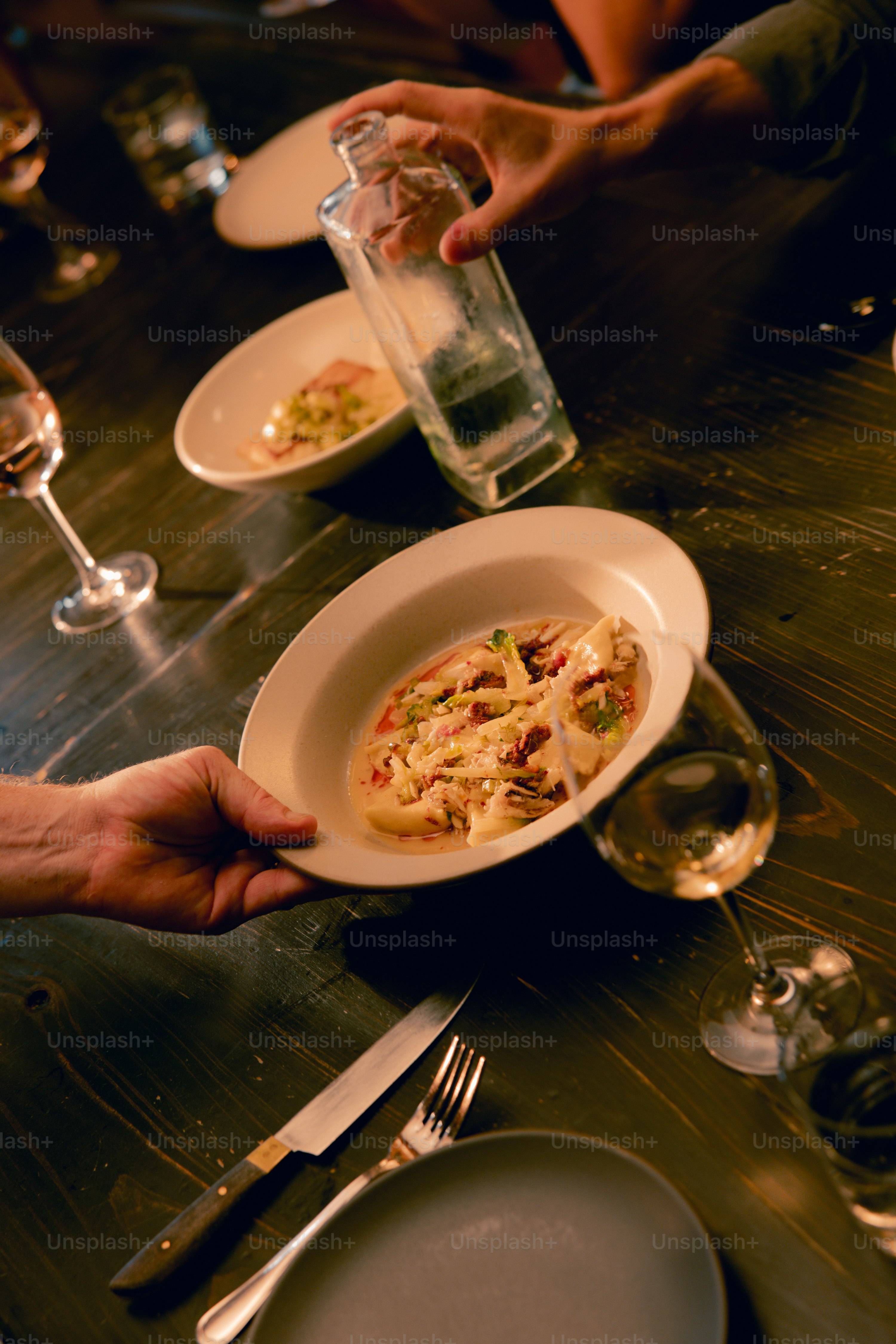 A person holding a plate of food at a table
