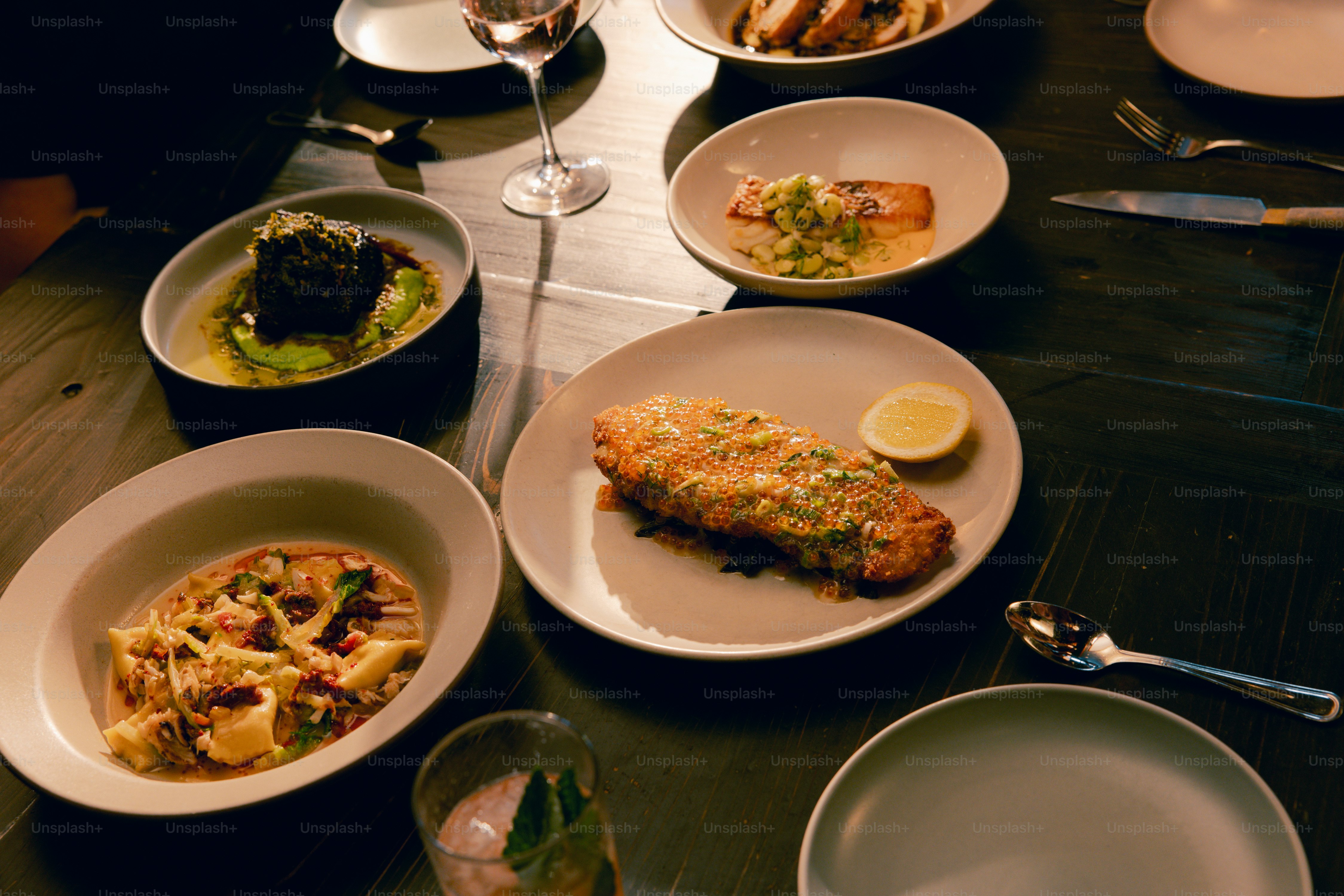 A table topped with plates of food and glasses of wine