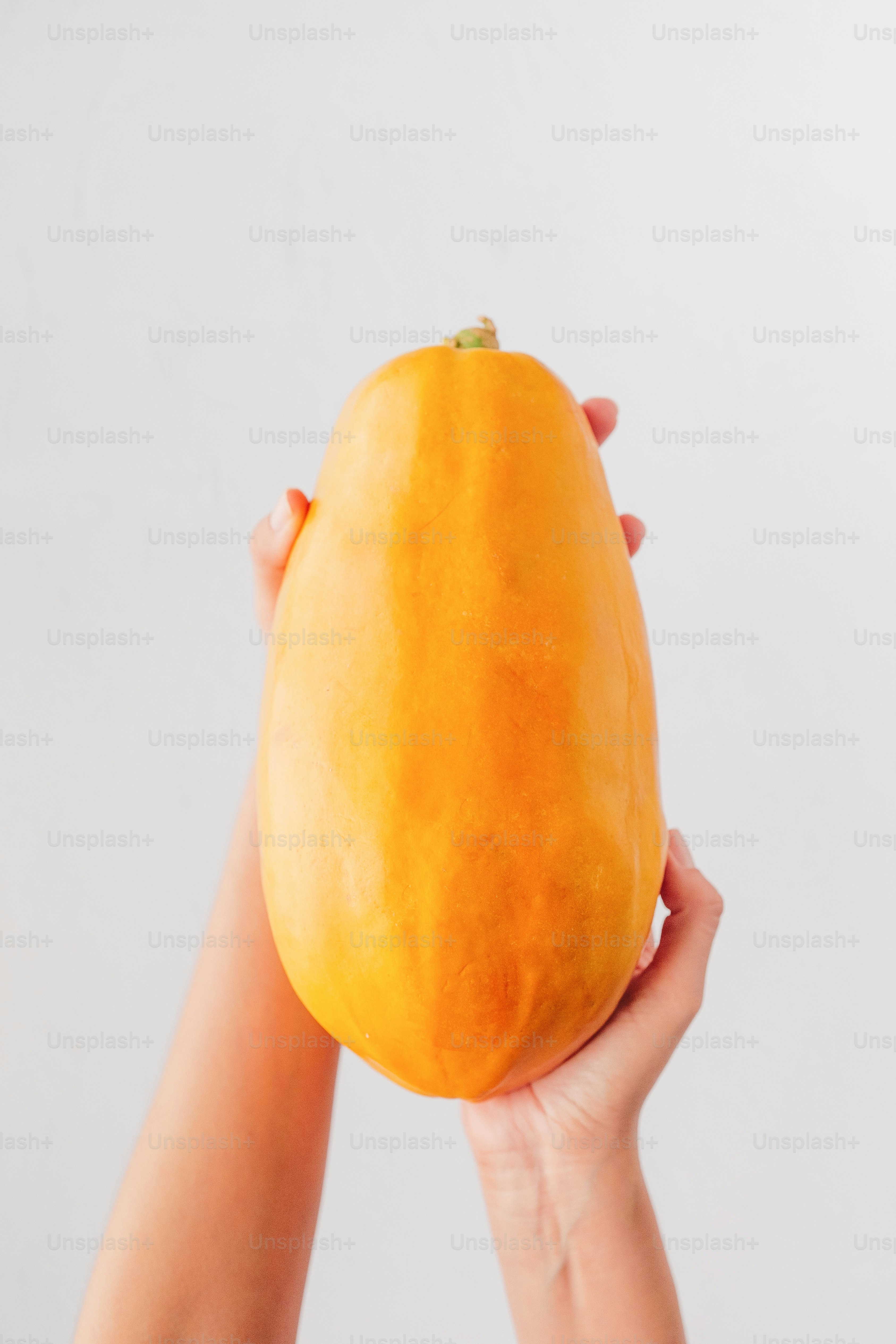 A person holding a mango in their hands