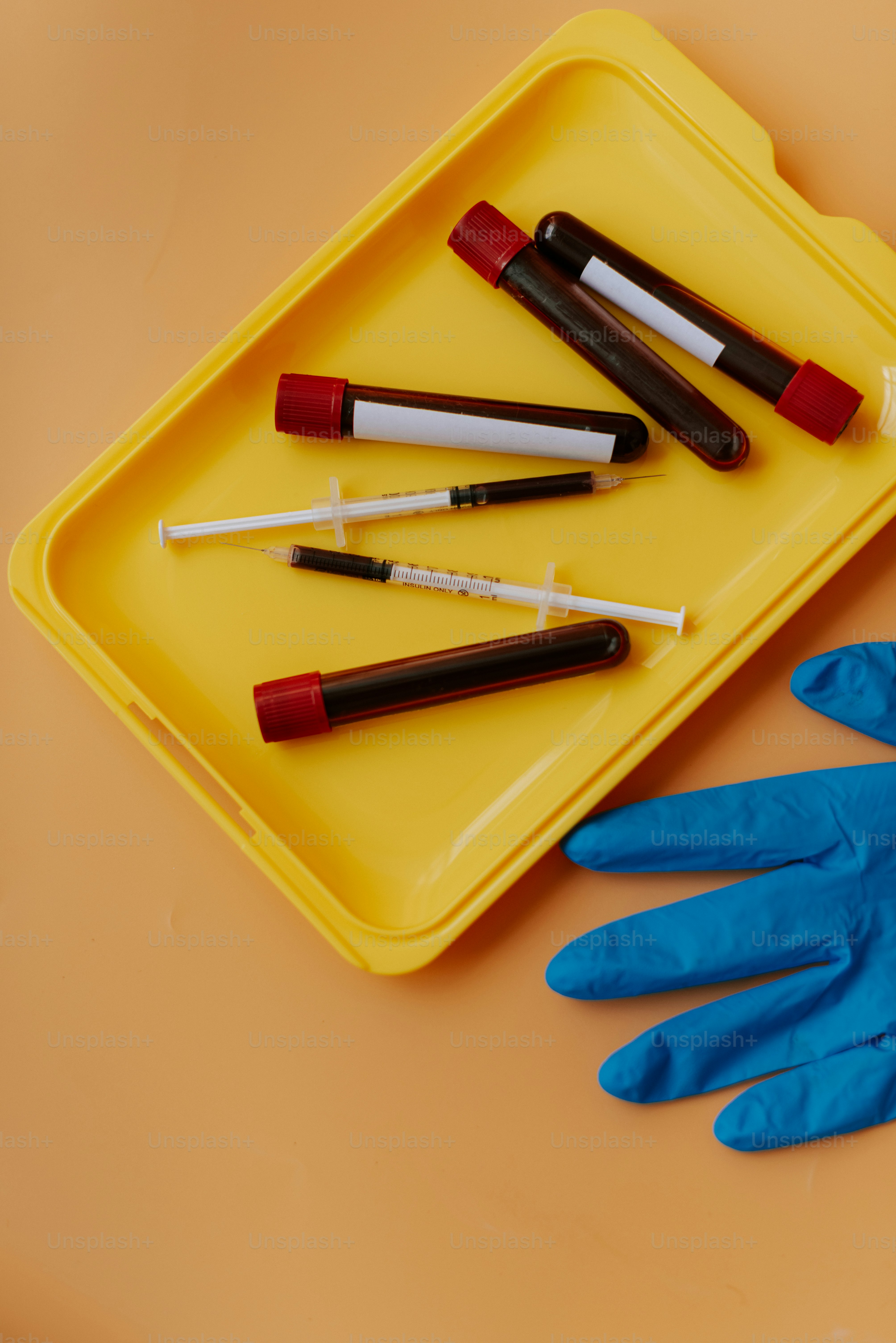Ein gelbes Tablett mit blauen Handschuhen und ein gelbes Tablett mit roten und weißen Röhren und