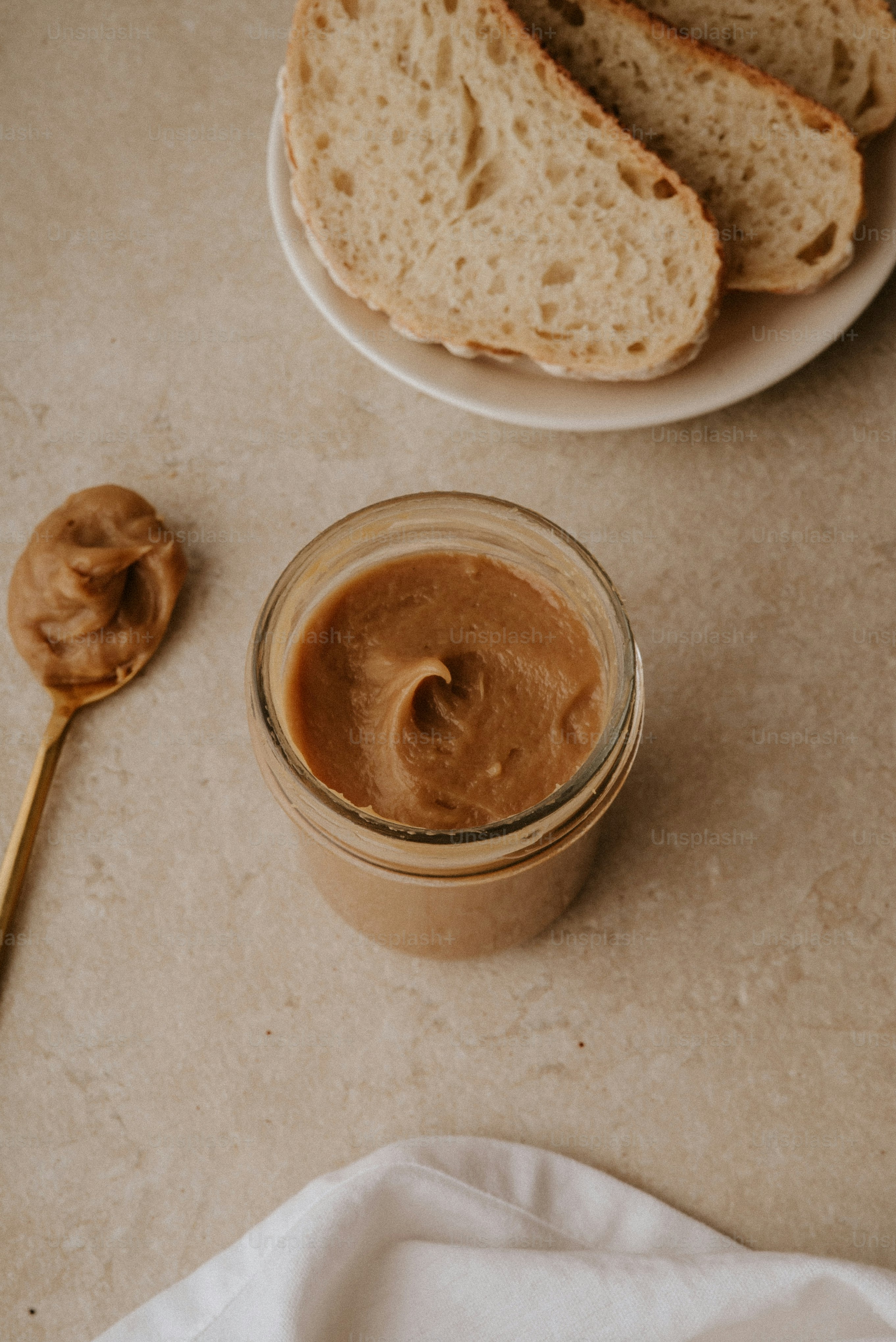A jar of peanut butter next to a plate of bread