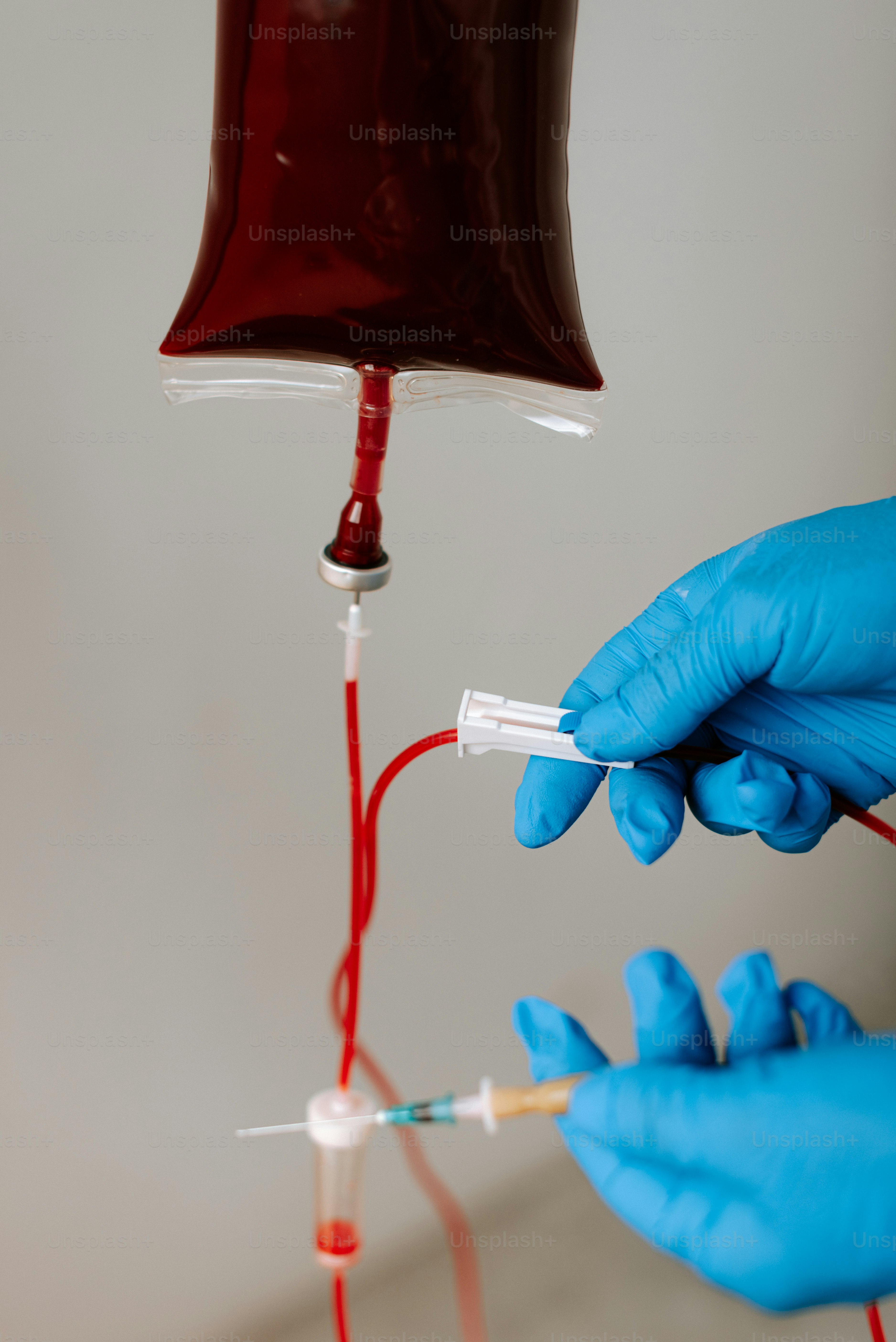 A person in blue gloves is holding a needle