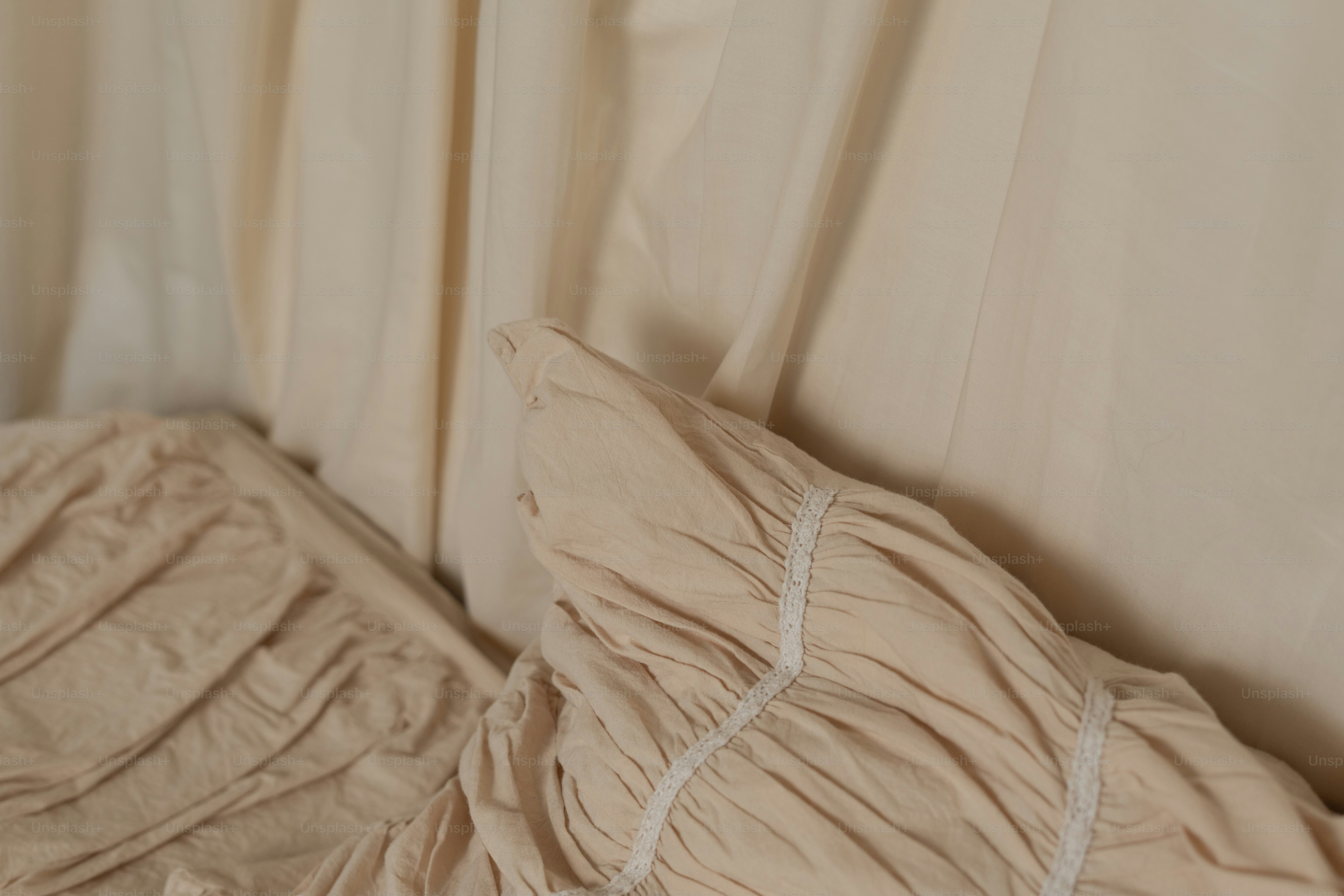 A bed with a white comforter and a white curtain