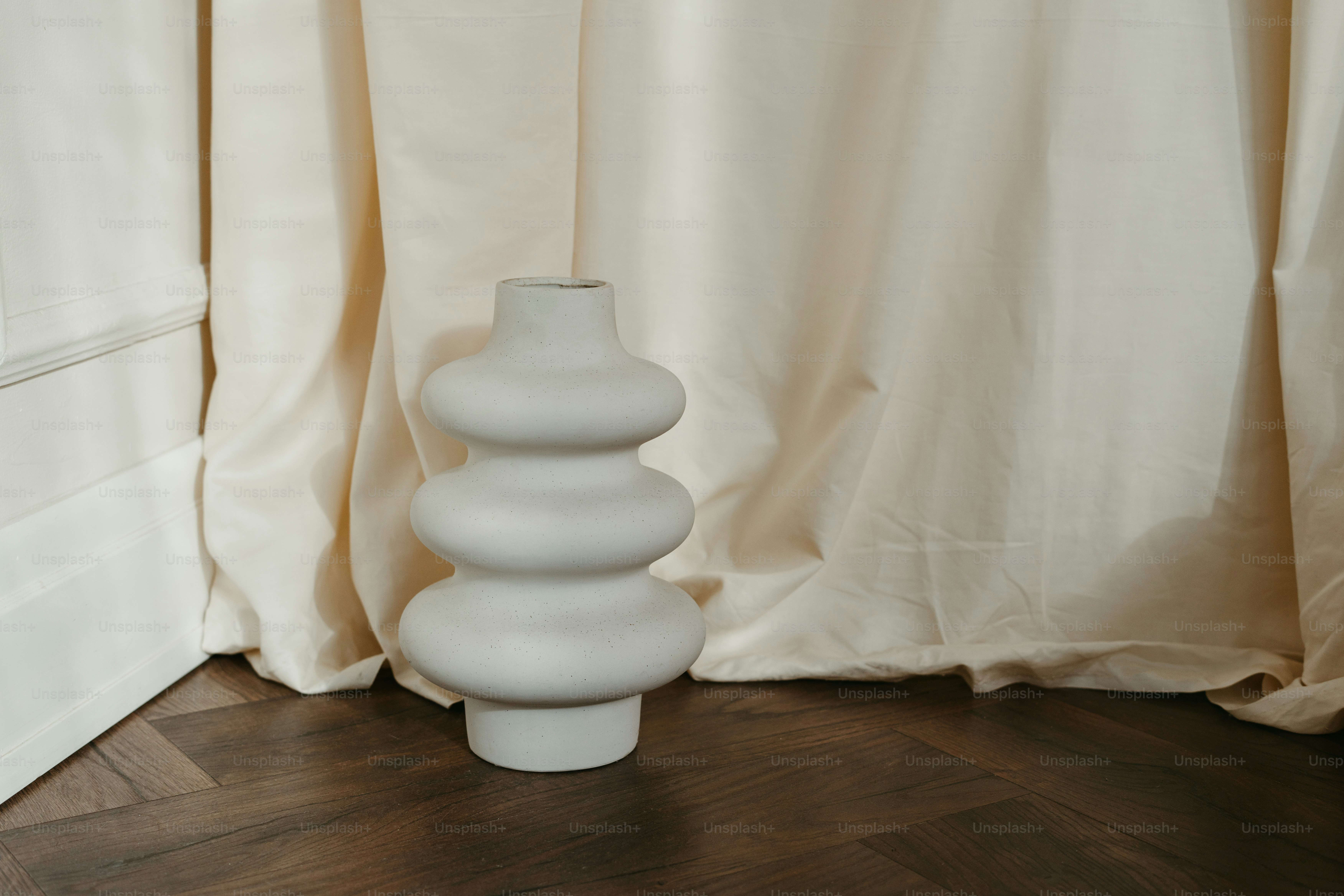 A white vase sitting on top of a wooden floor