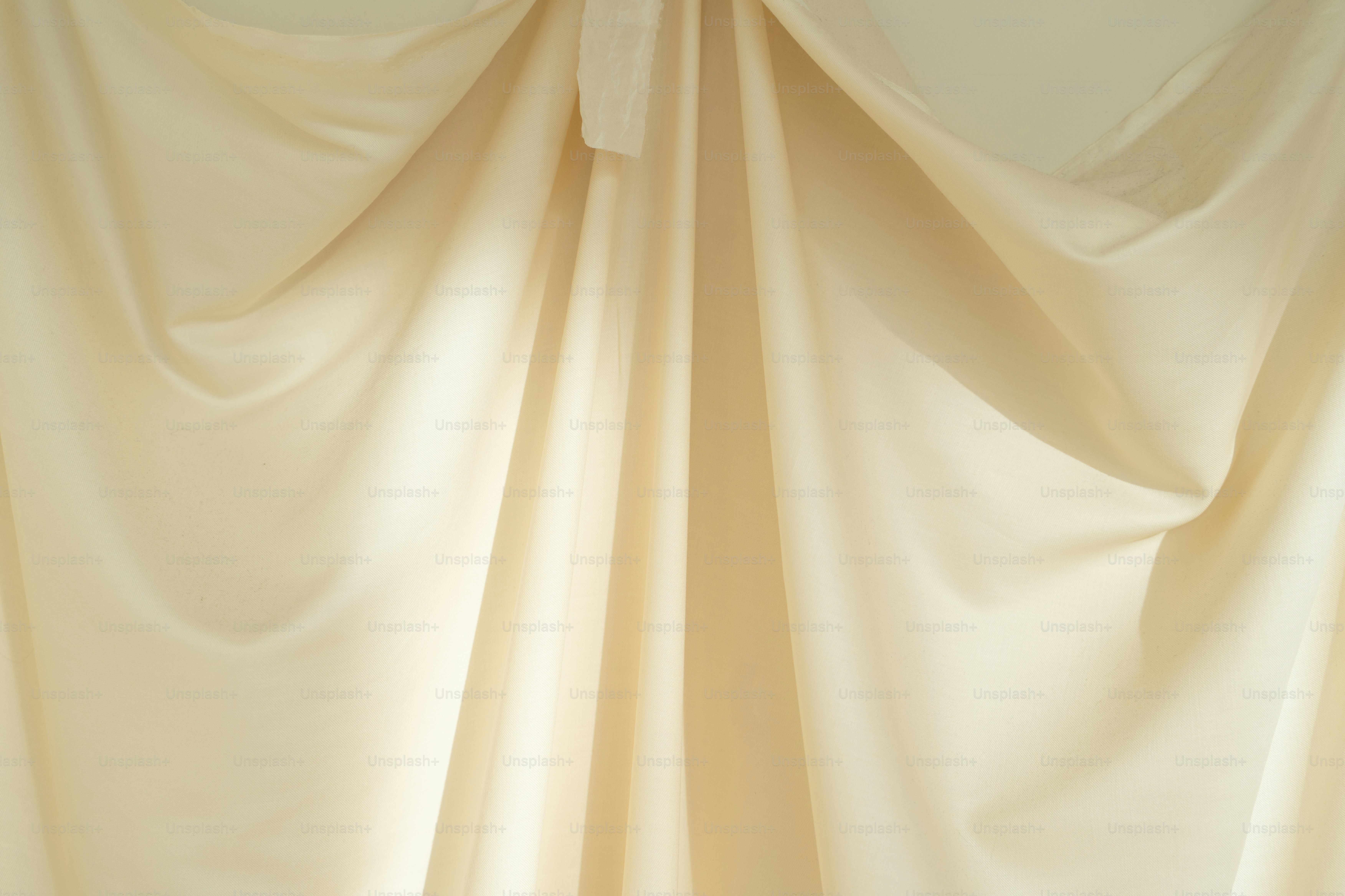 A room with a white curtain and a vase with flowers