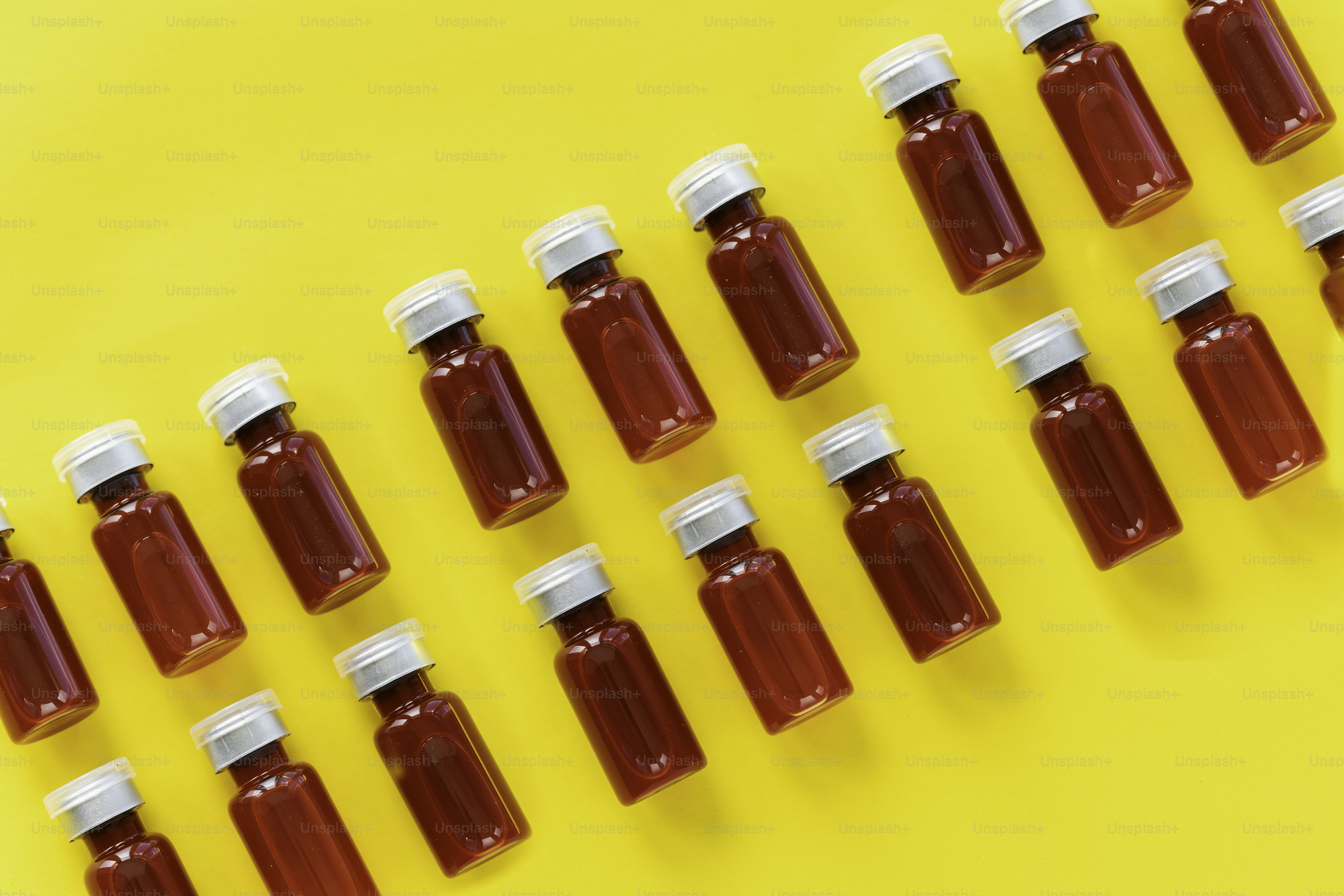 A row of bottles of red liquid on a yellow background