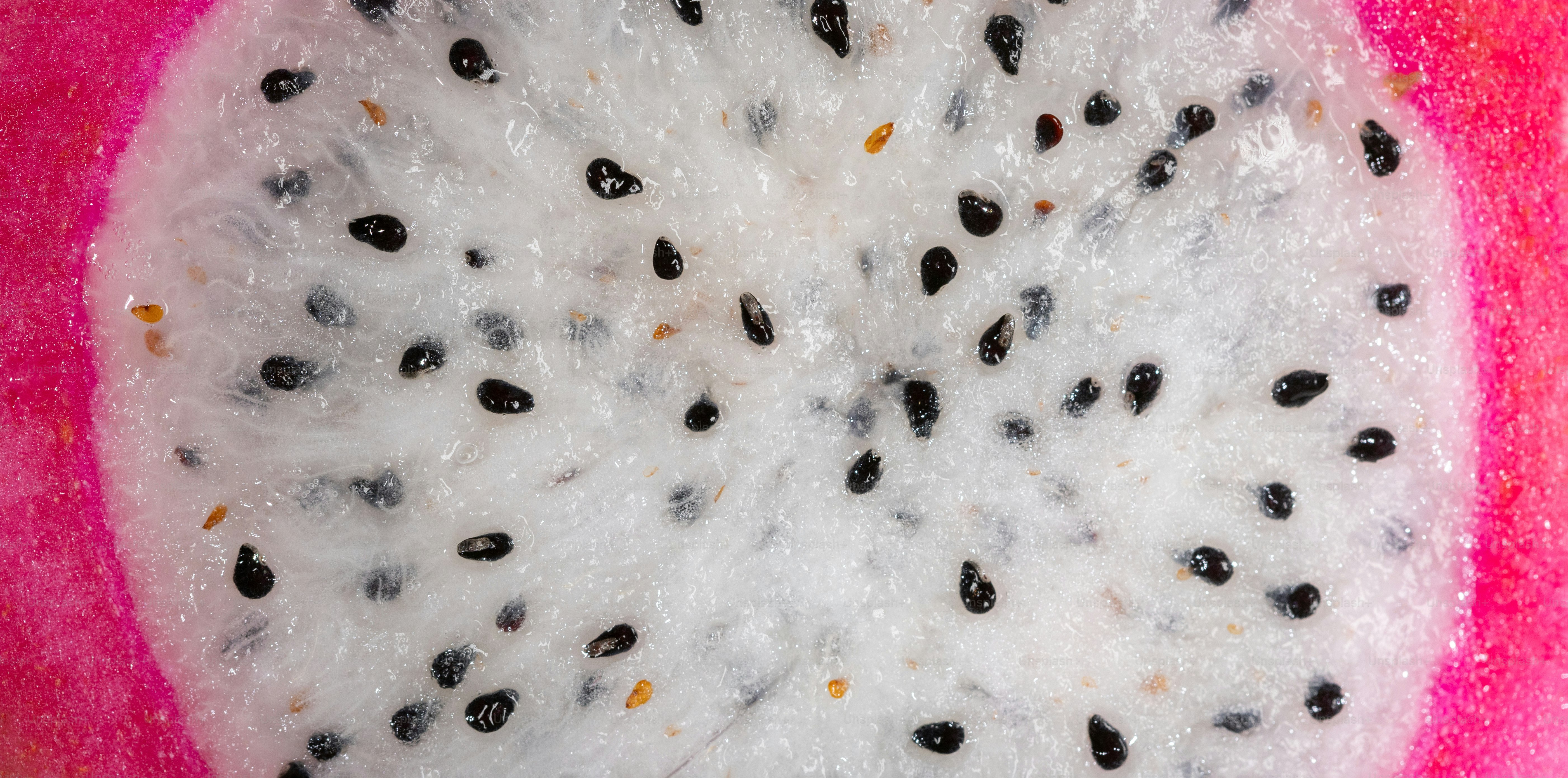 A close up of a kiwi fruit on a pink surface