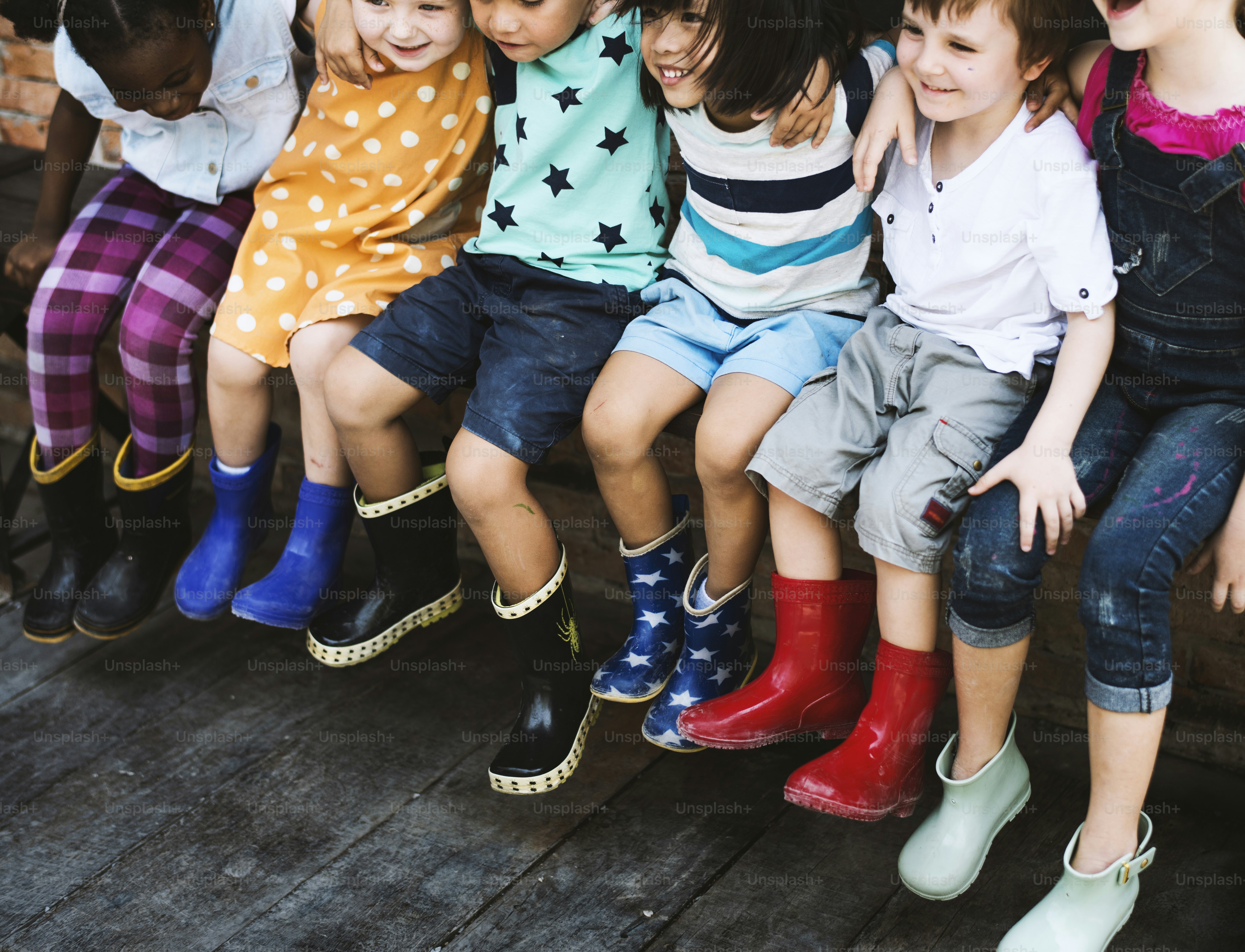 Cheerful kindergarten kids friends arm around sitting