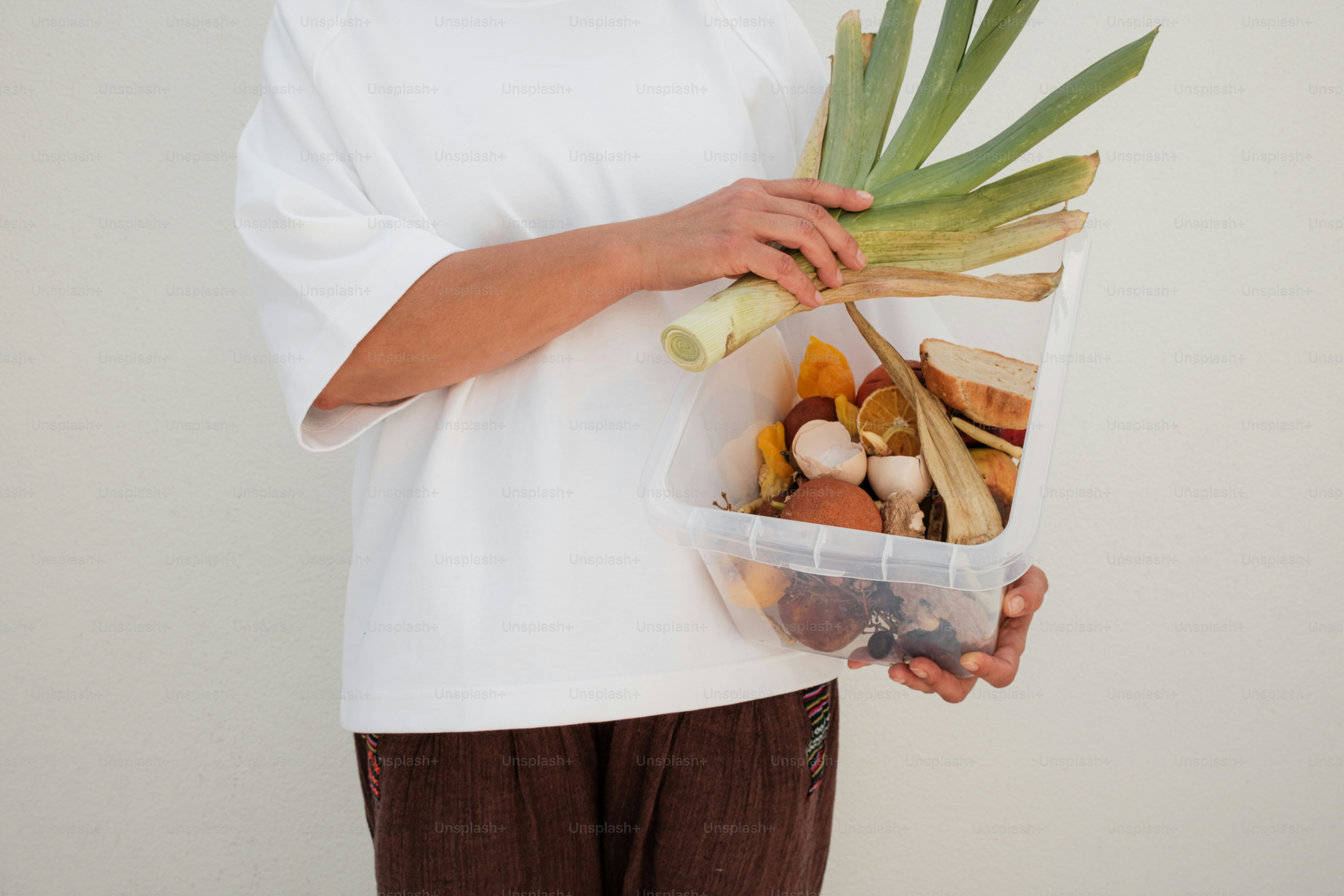 A woman holding a plastic container filled with vegetables