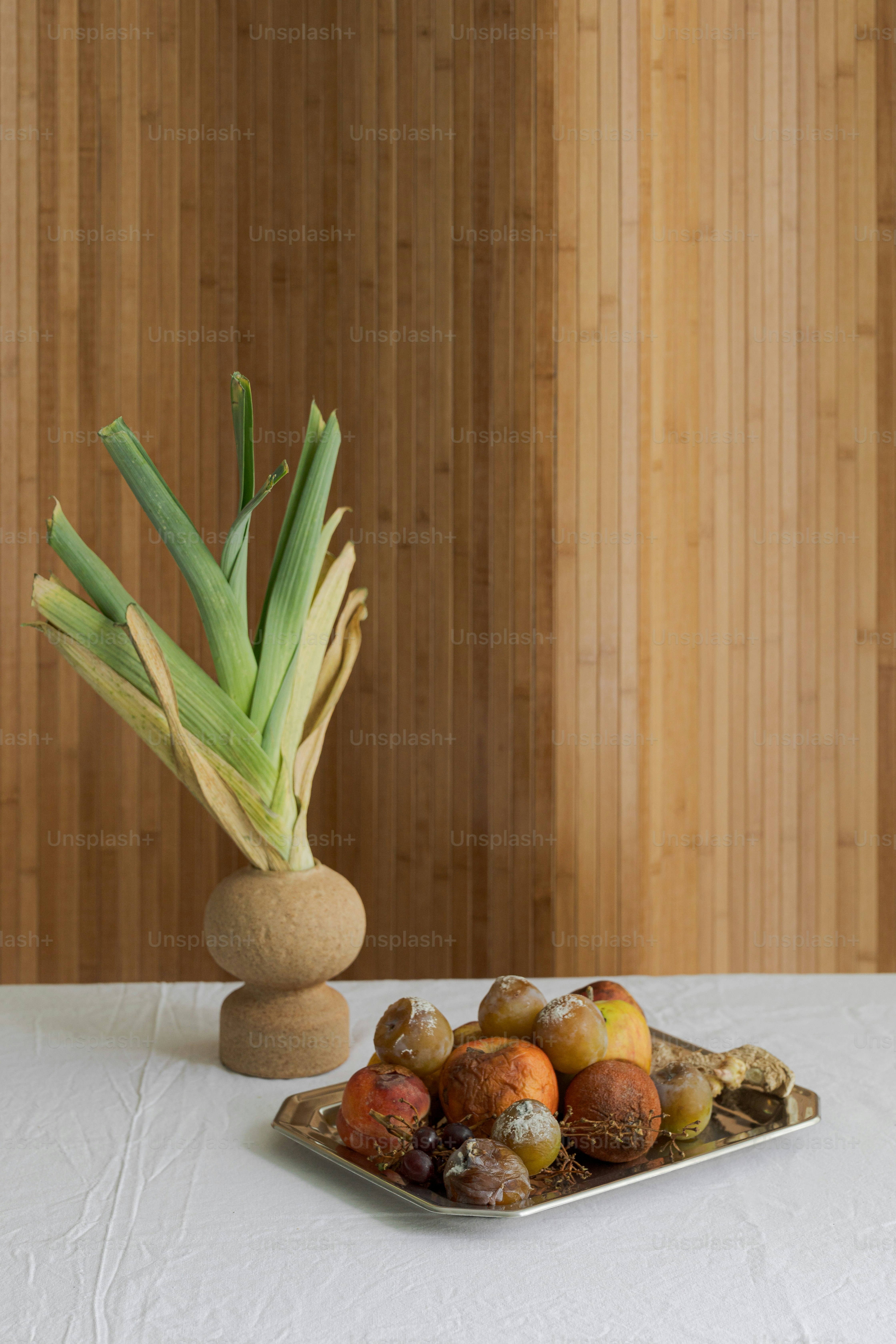 A plate of fruit and a vase of flowers on a table