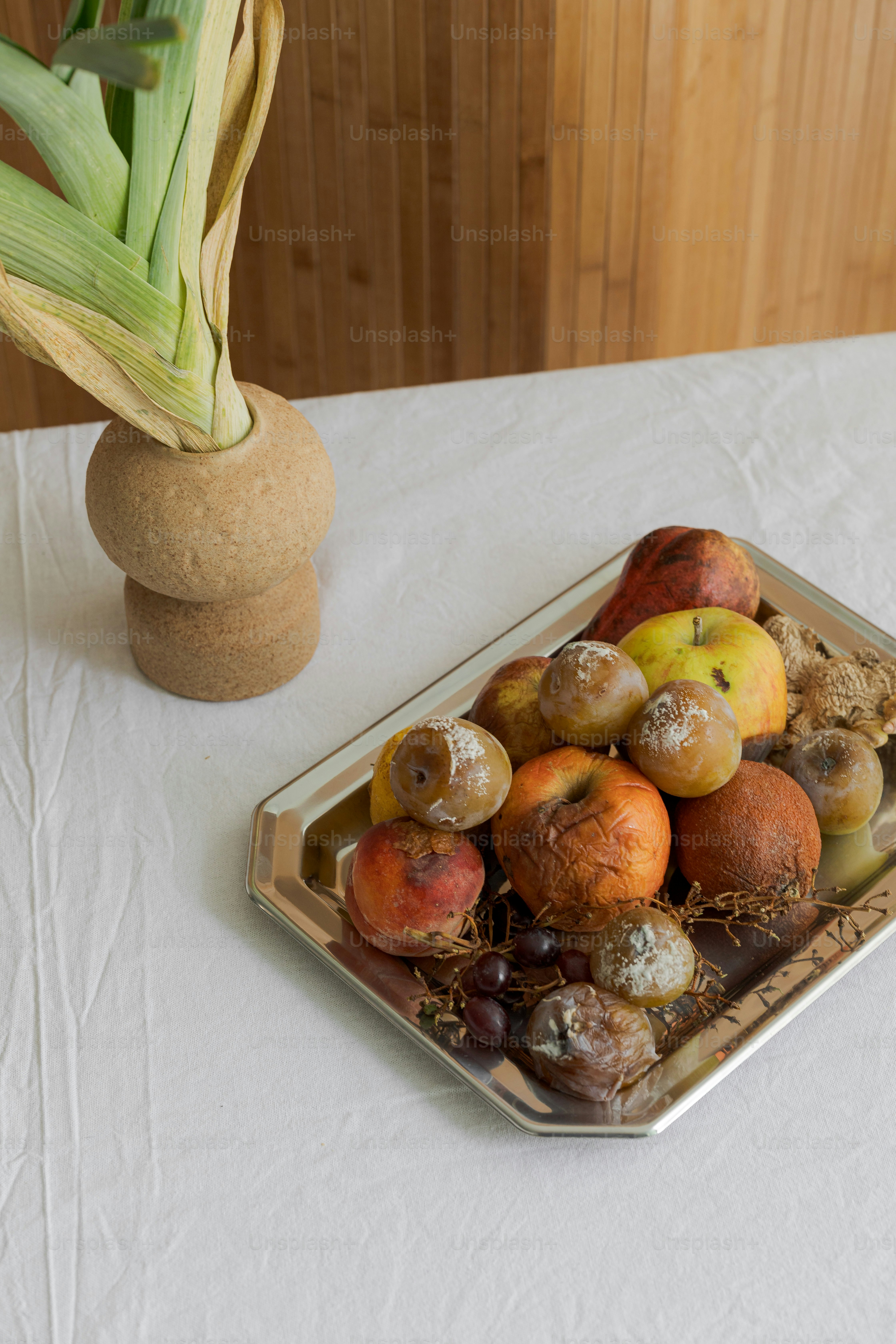 Ein Tablett mit Obst steht auf einem Tisch neben einer Topfpflanze