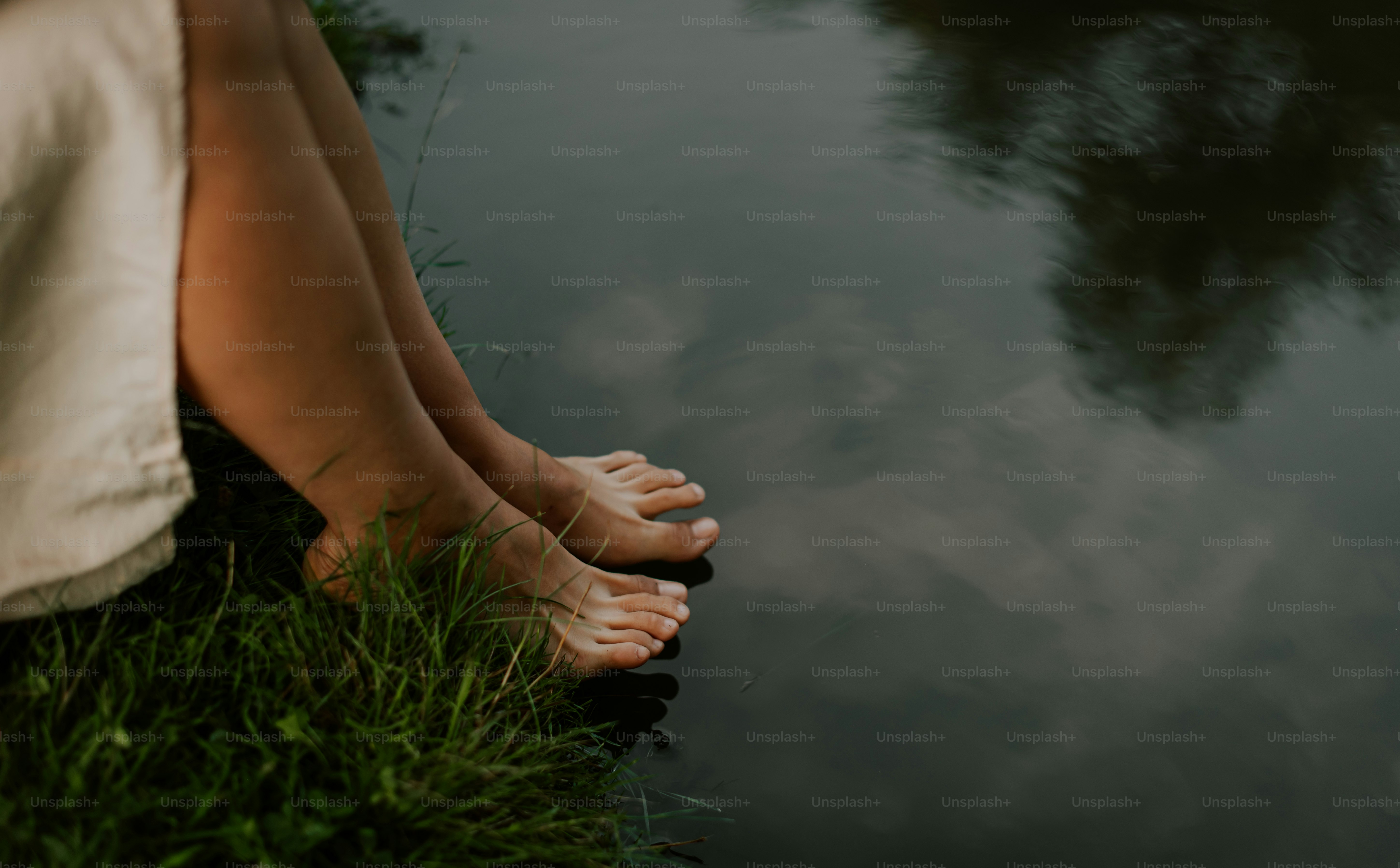 A person sitting on the grass next to a body of water