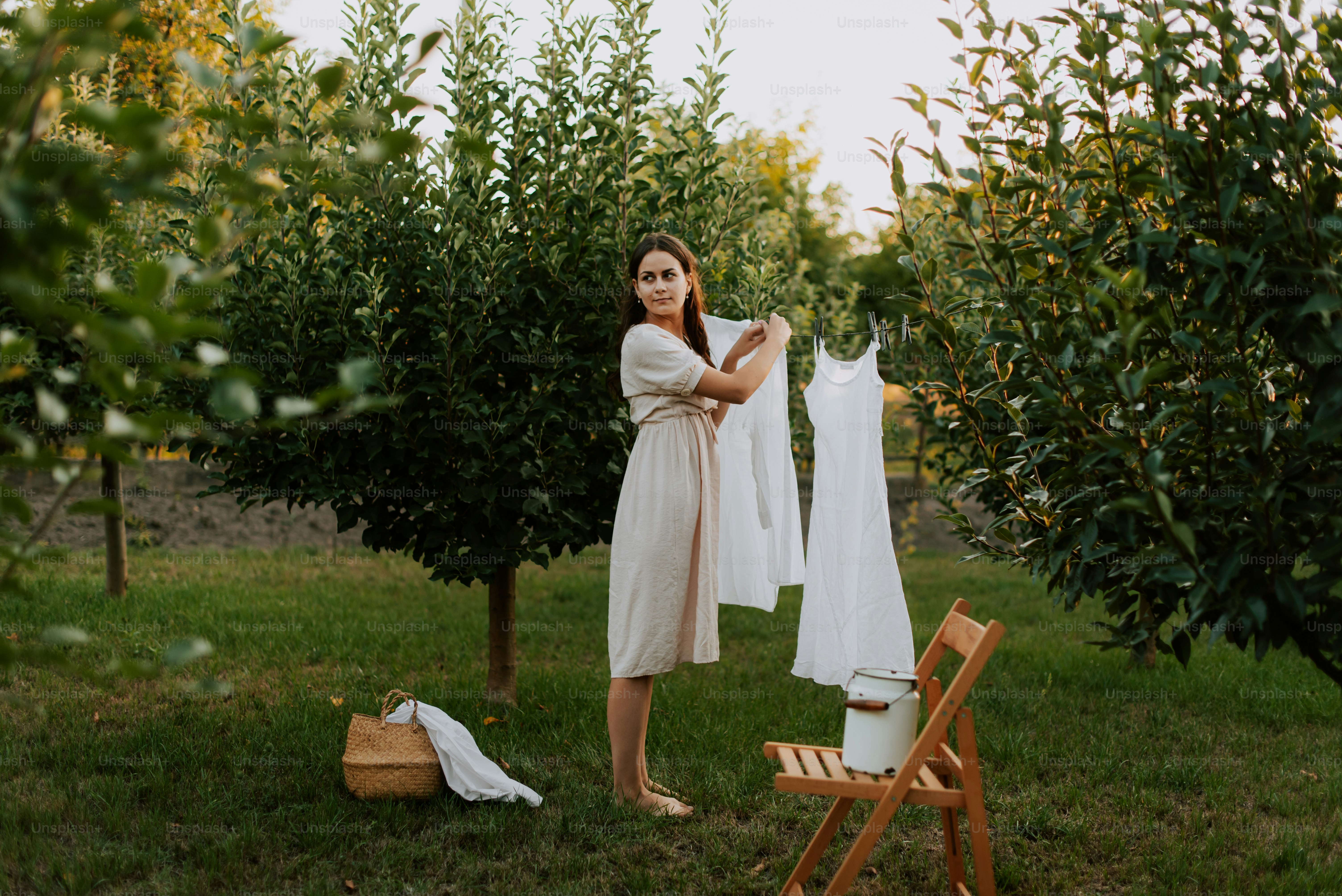 A woman standing next to a tree holding a white dress