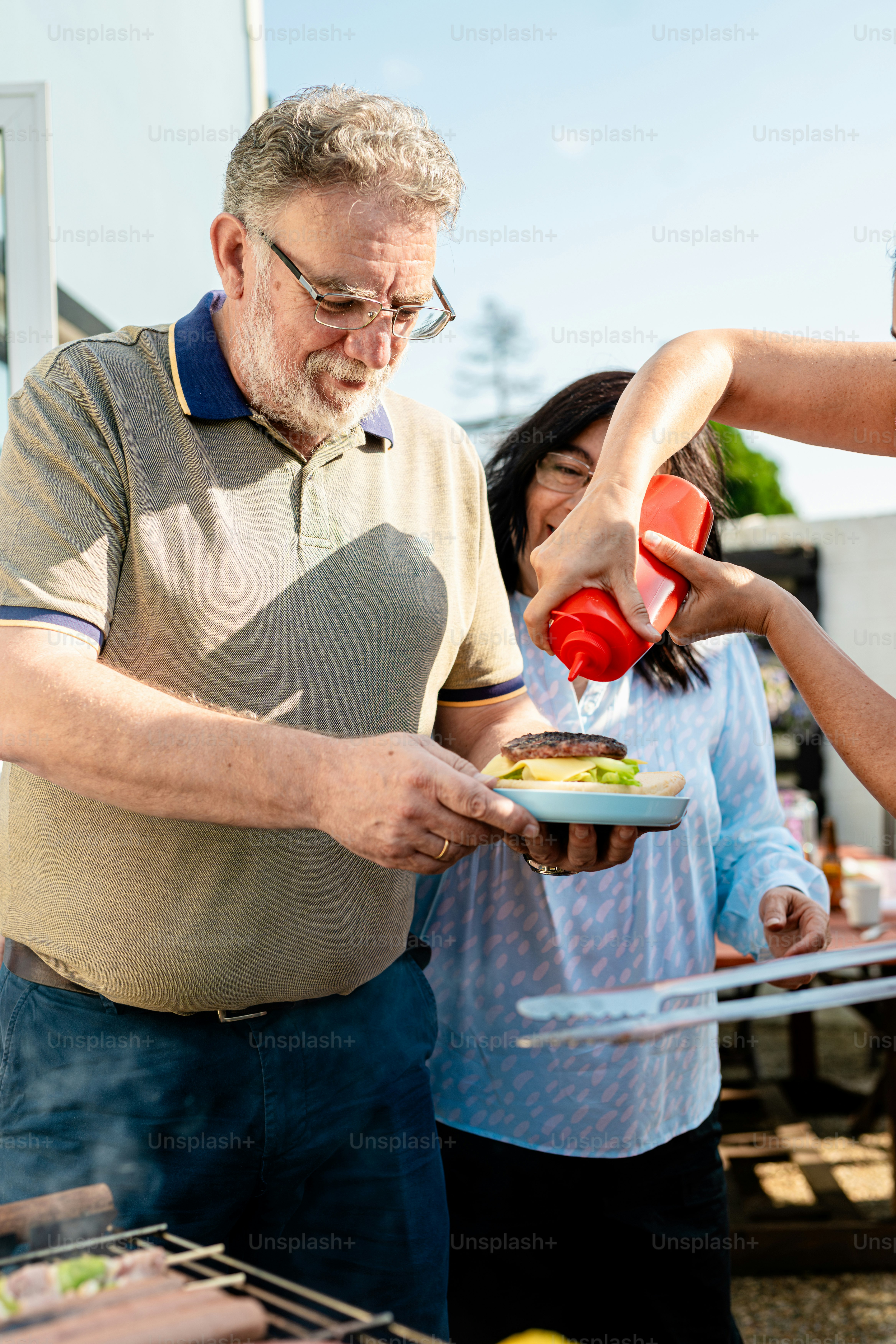 A group of people standing around a bbq grill