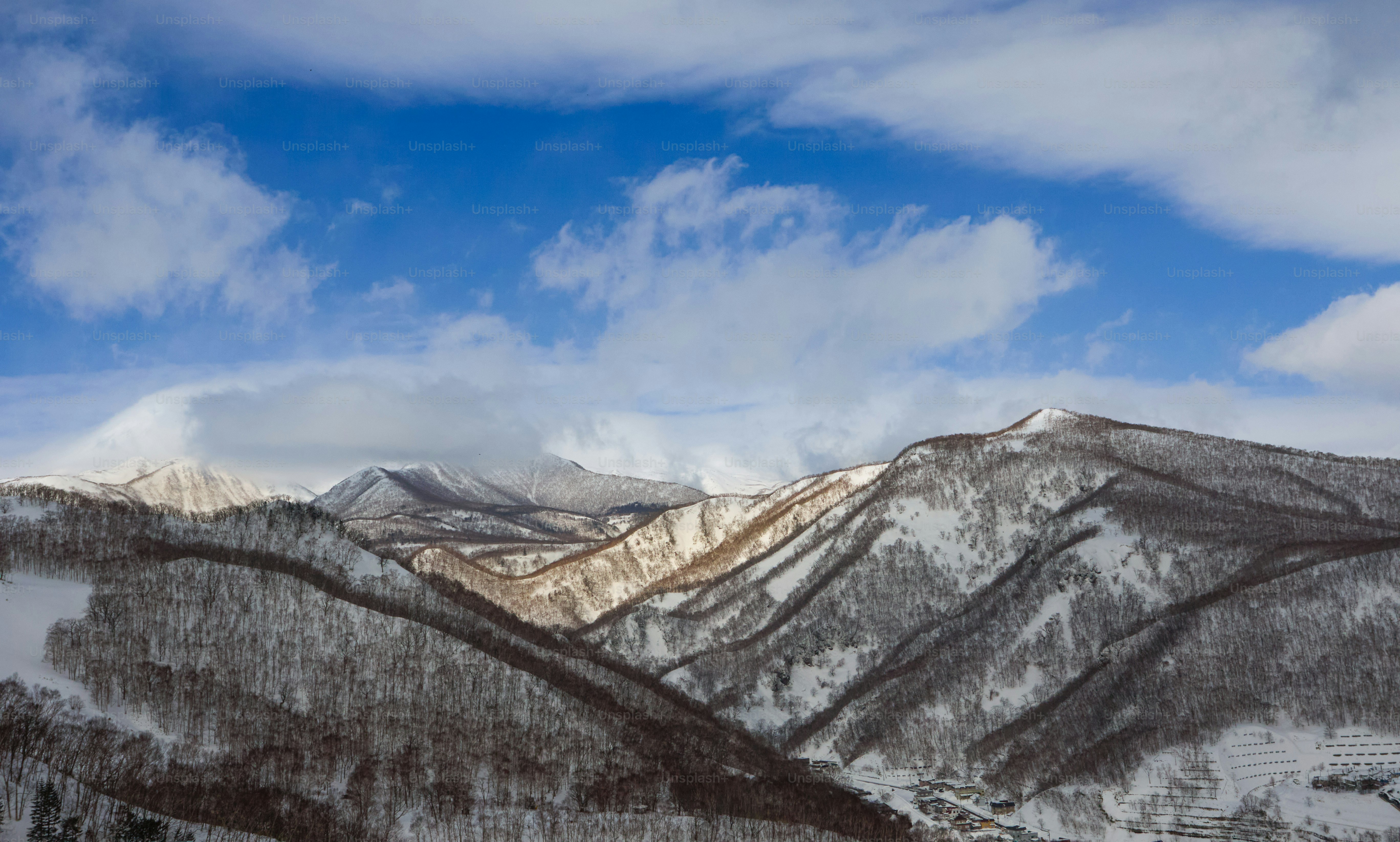 A snow covered mountain range under a cloudy blue sky
