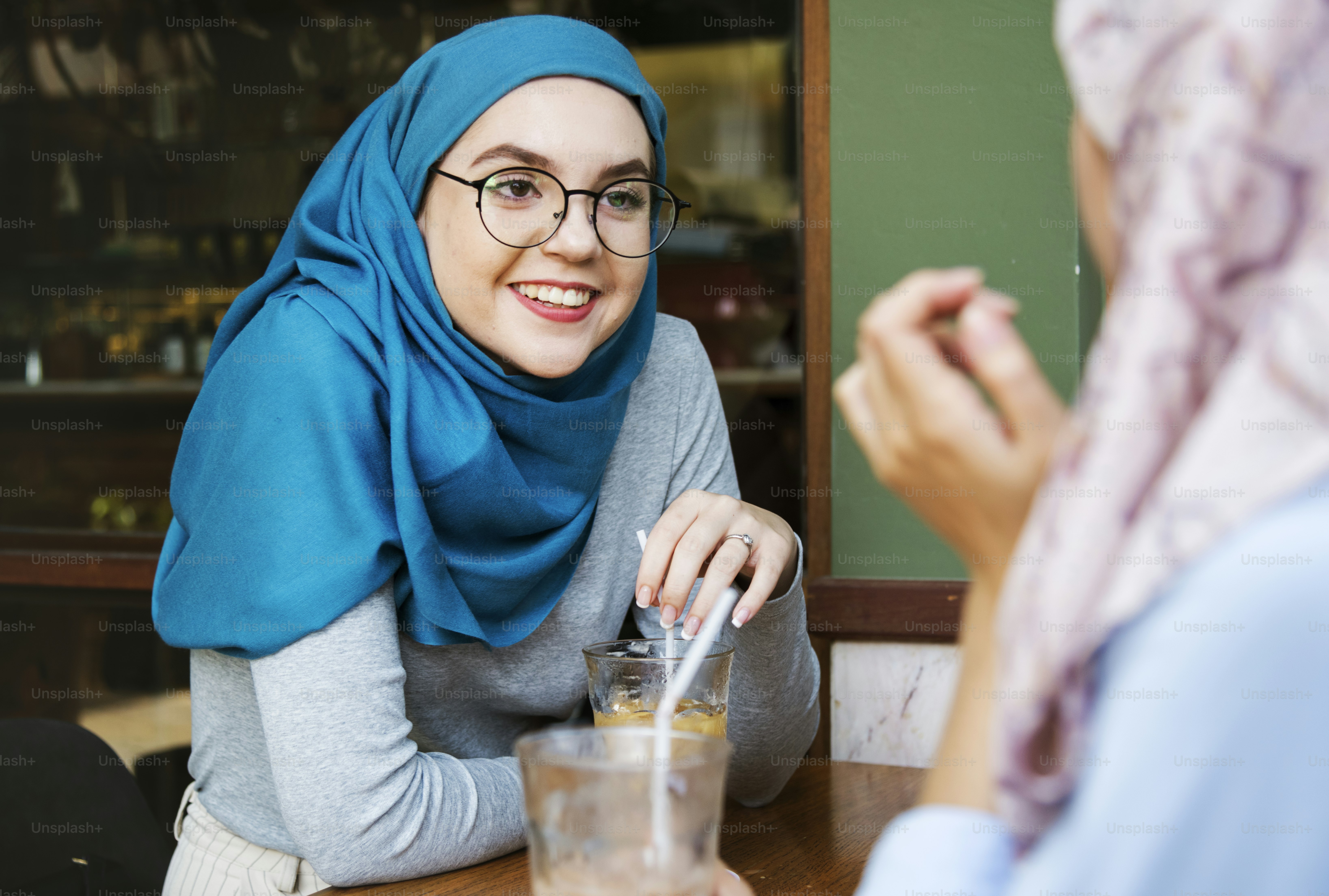 コーヒーショップで楽しんで話しているイスラム教の女性友達