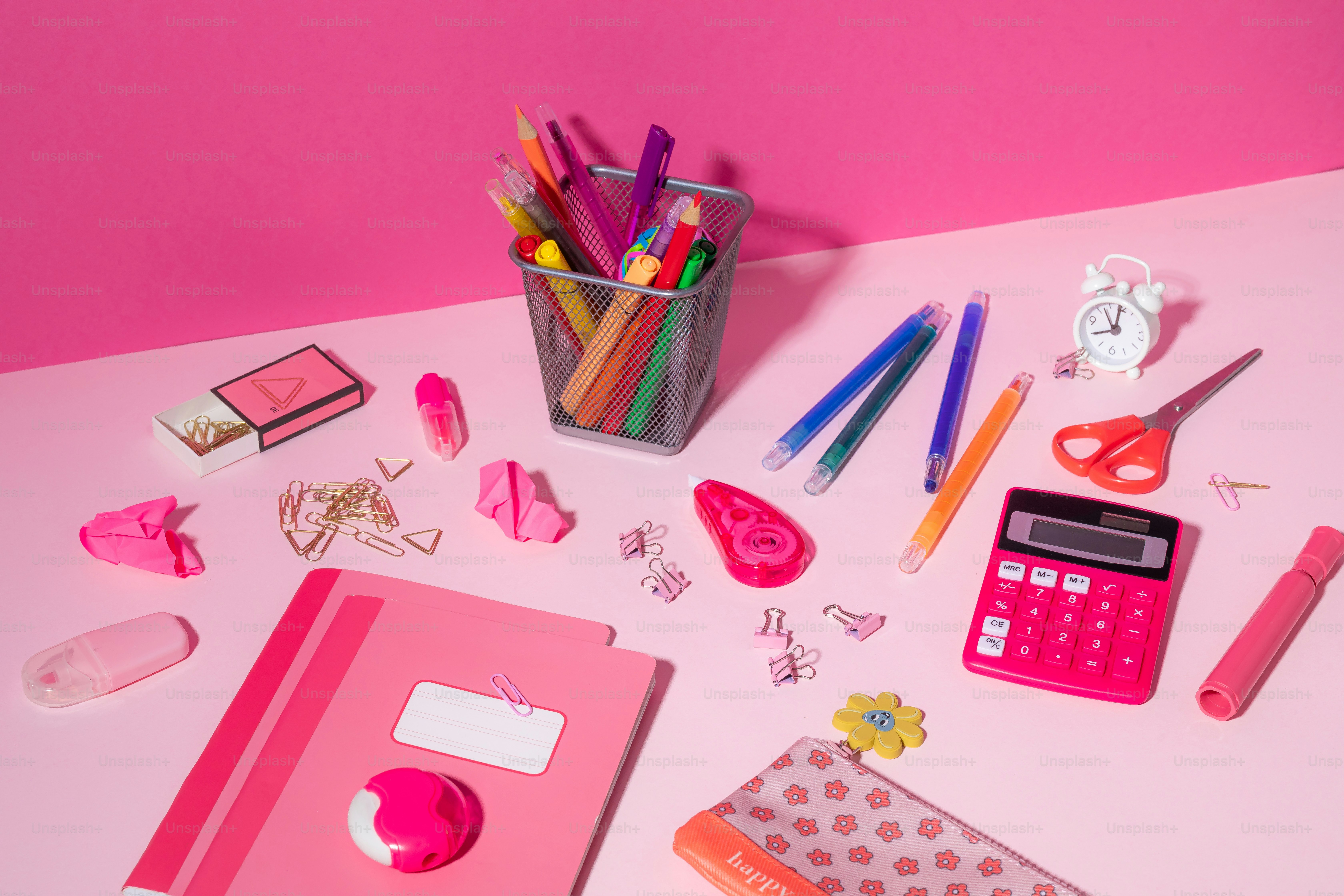 A pink desk topped with lots of office supplies