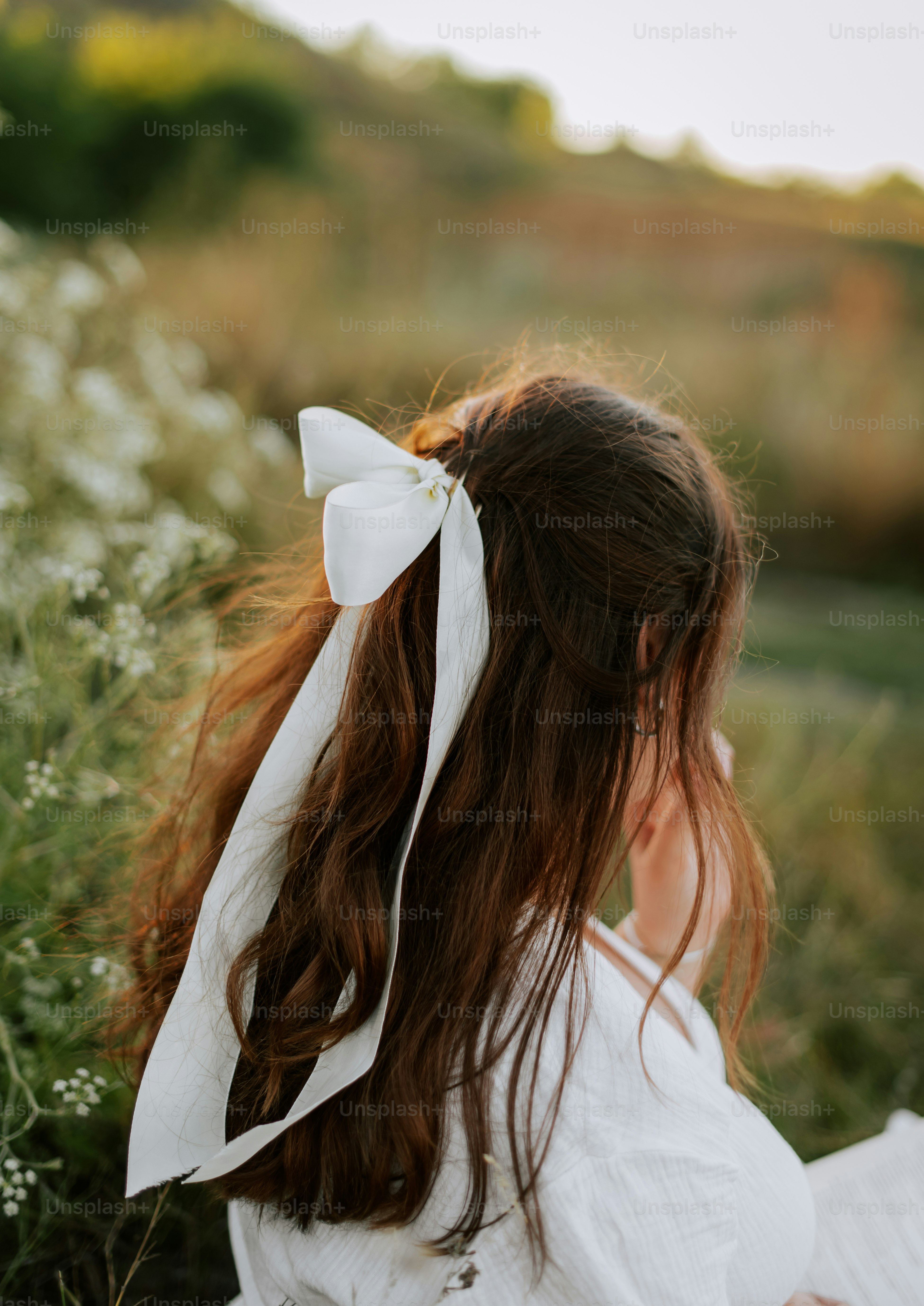 A little girl in a white dress sitting in a field