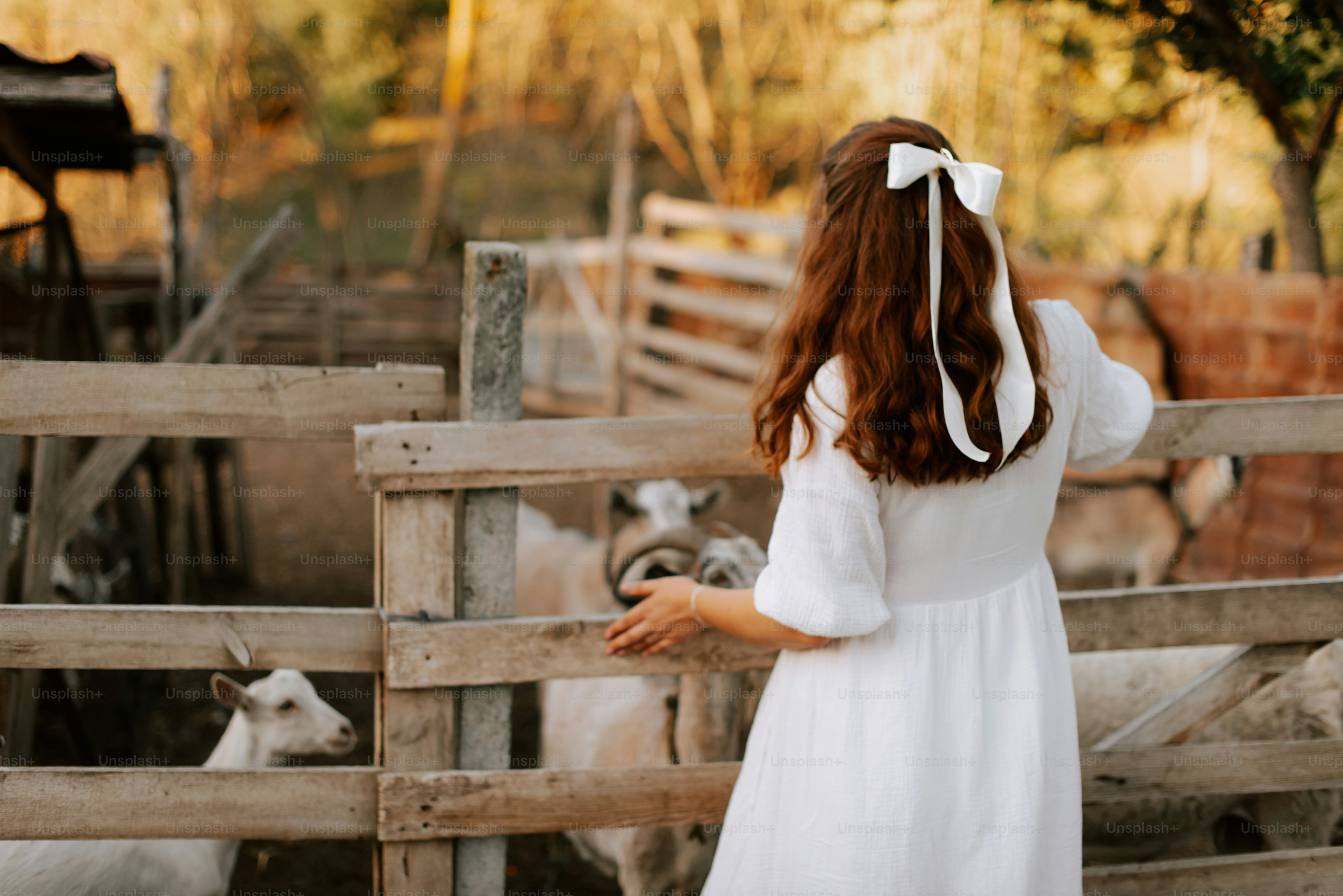 A woman in a white dress standing next to a fence