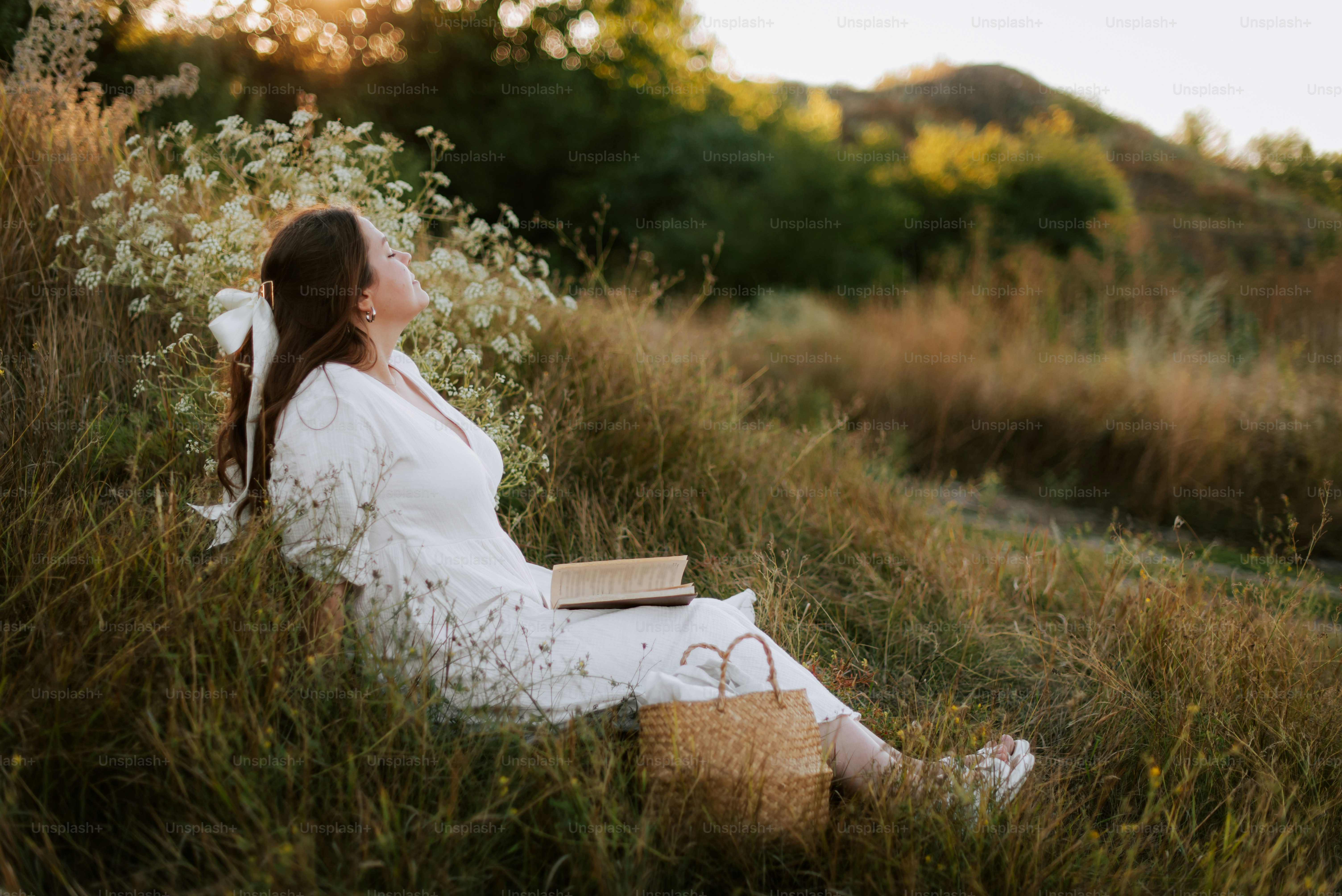 Una mujer sentada en un campo con un libro