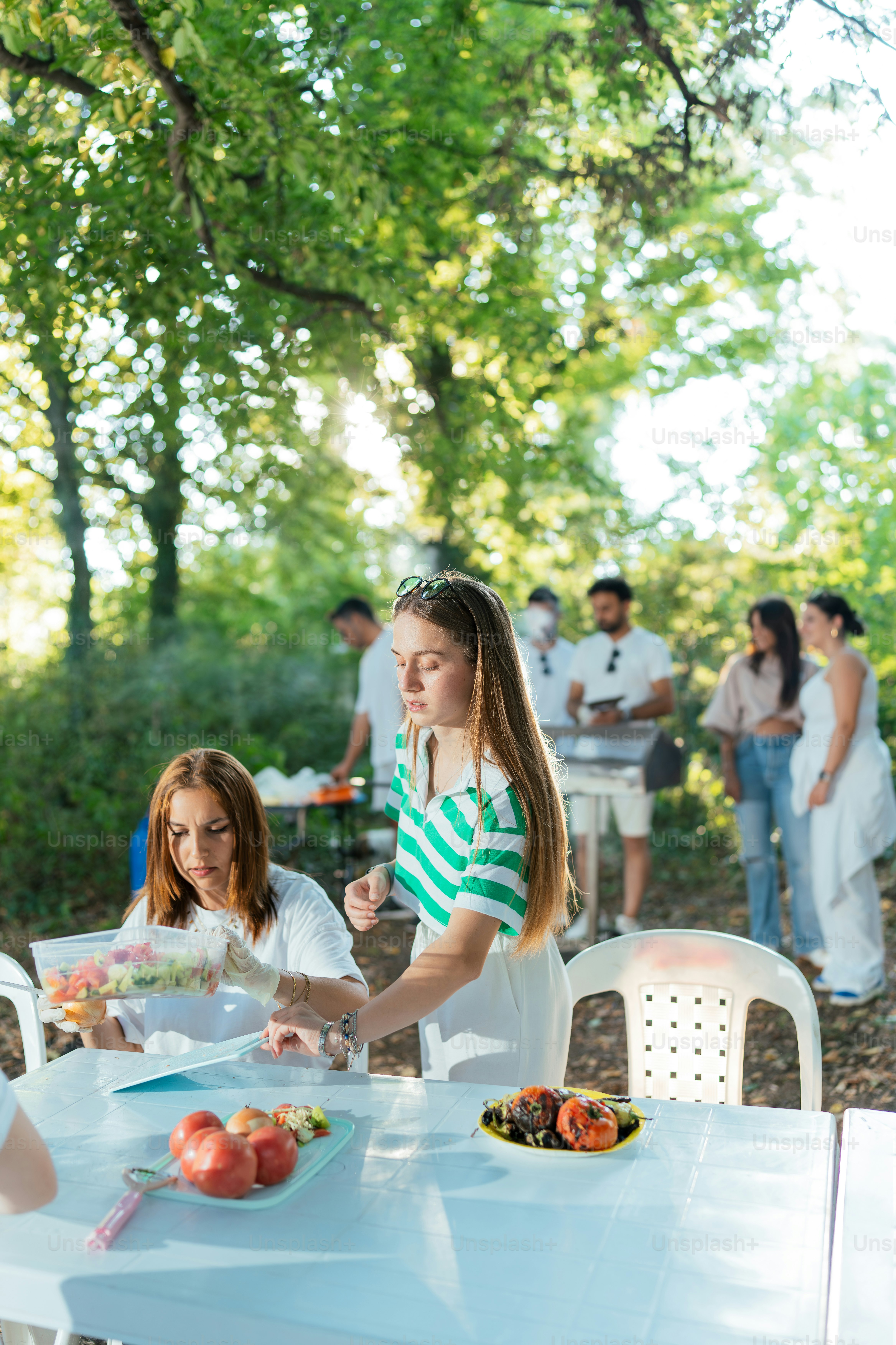 A group of people standing around a table with plates of food on it ...