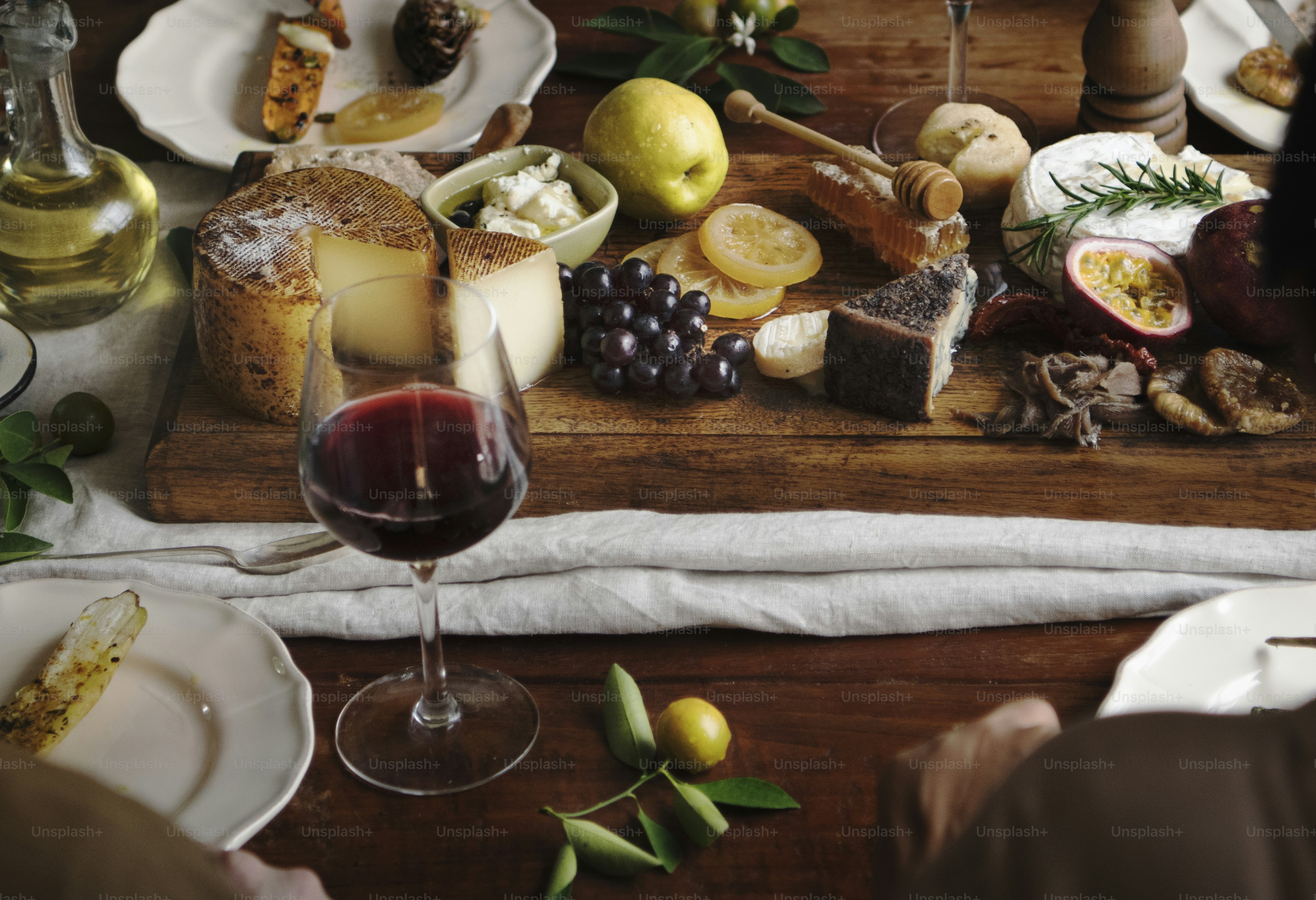 Des gens mangent un plateau de fromages avec des fruits de saison et du vin