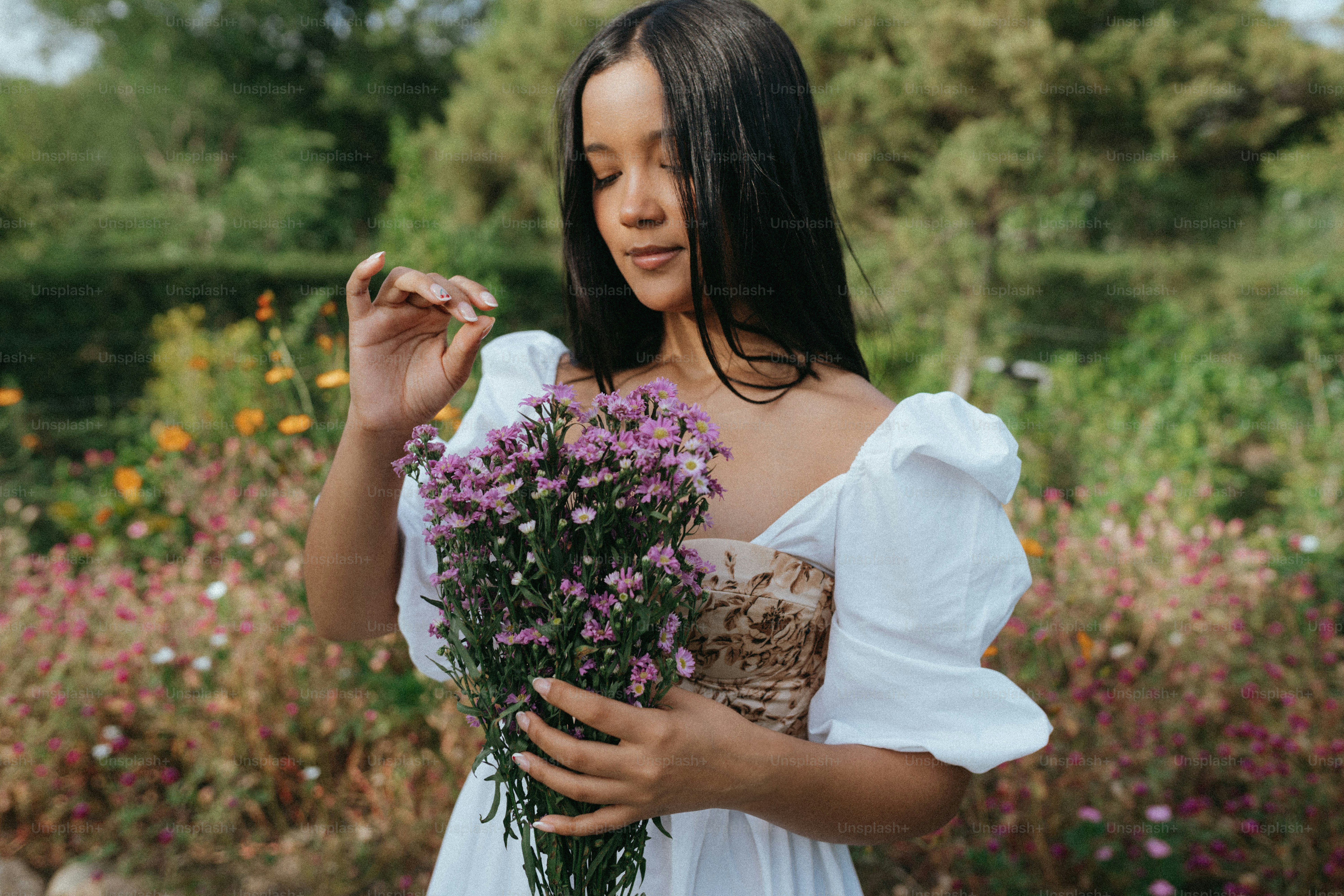 A woman in a white dress holding a bouquet of flowers photo – Bouquet ...