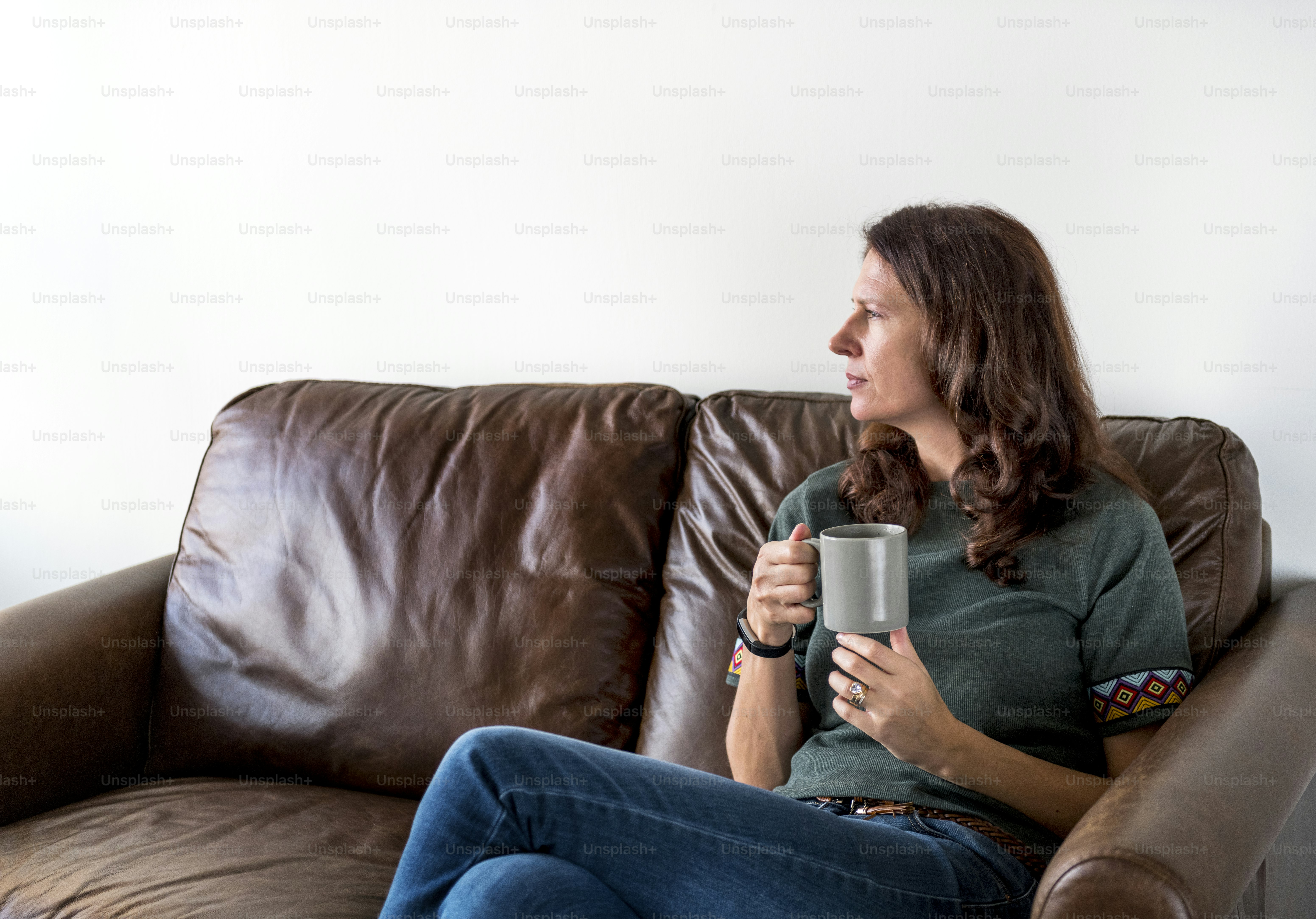 Thoughtful woman drinking tea or coffee sitting on a cozy couch