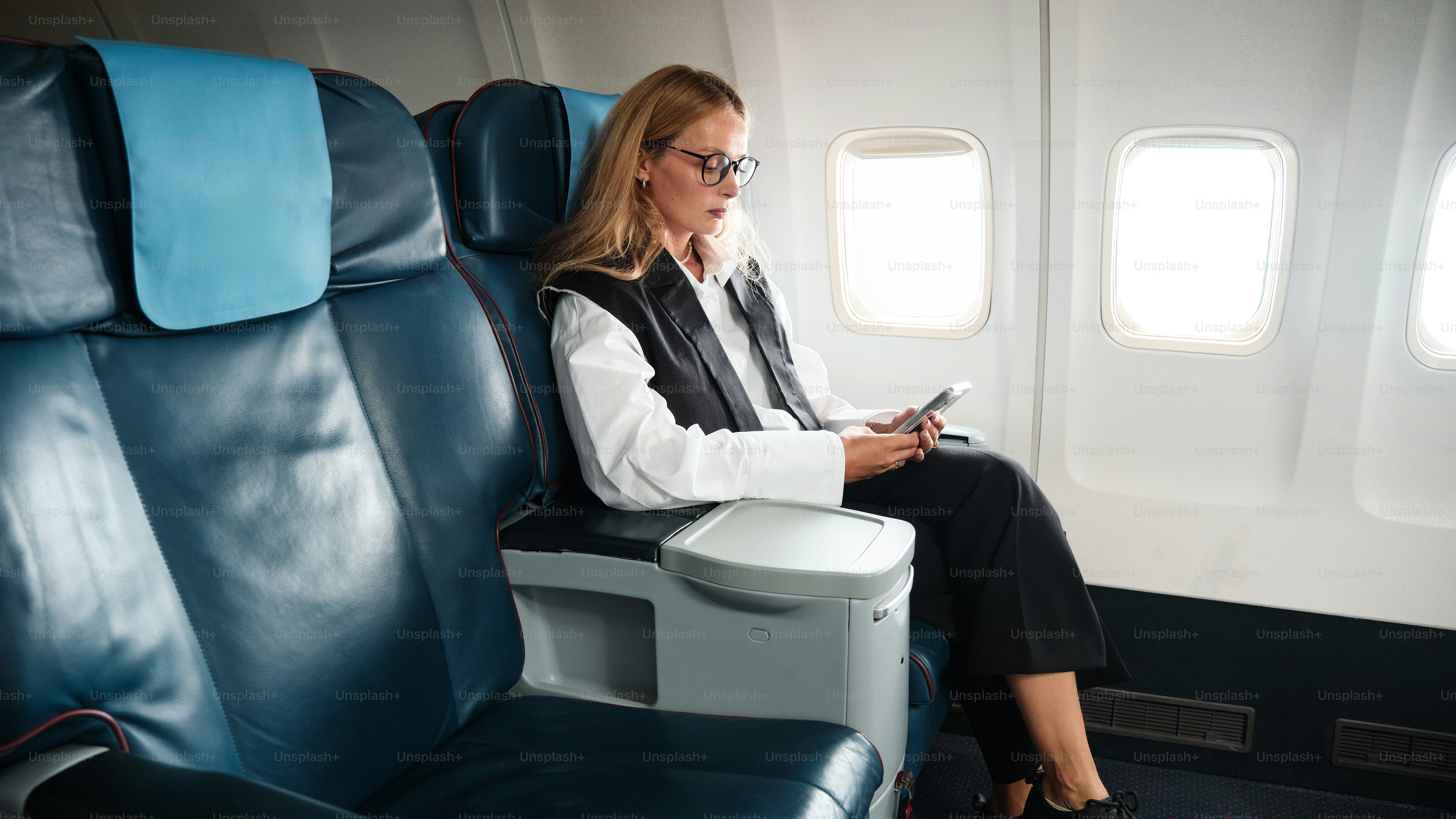 A woman sitting on an airplane looking at her cell phone