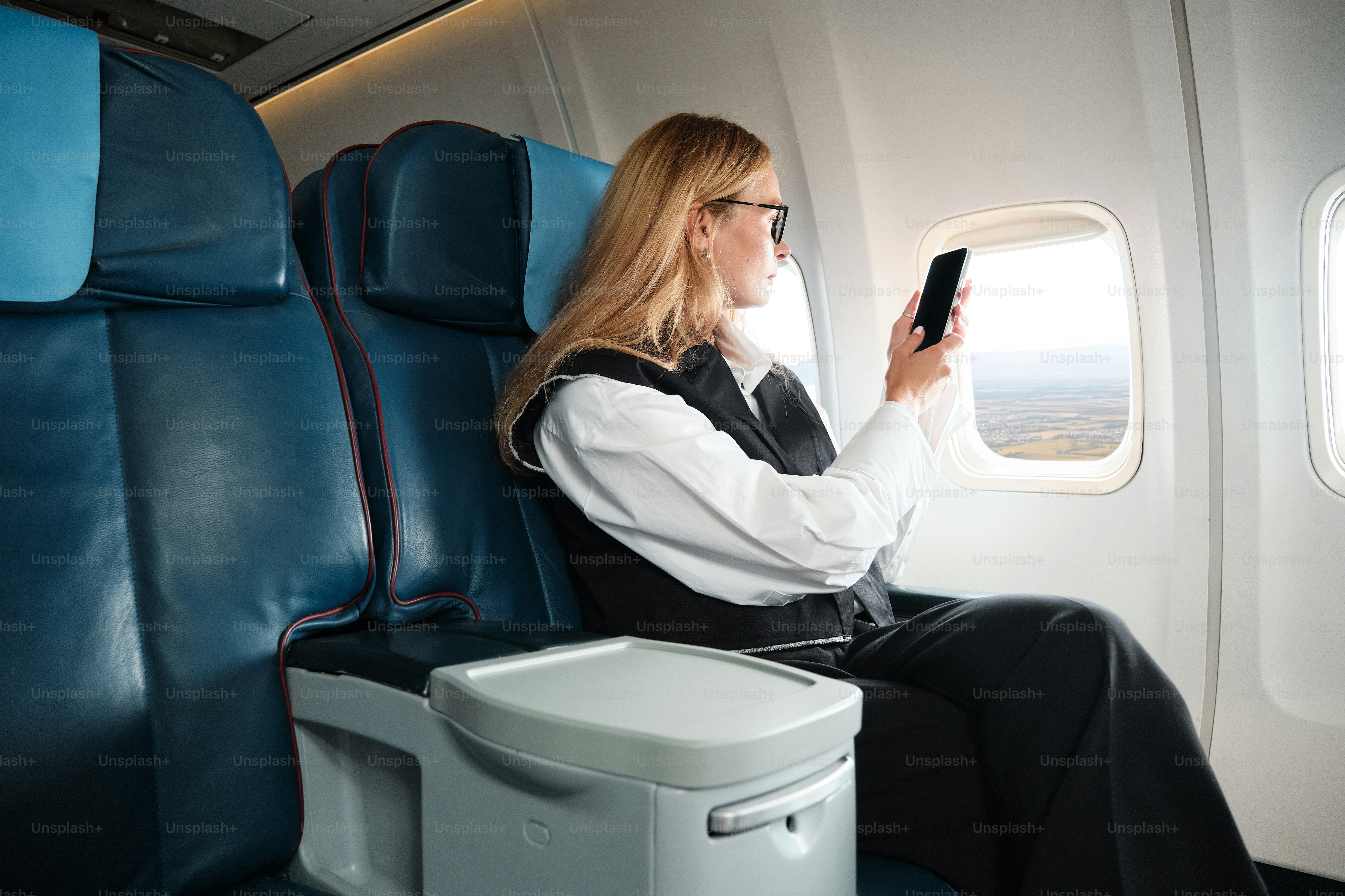 Une femme assise dans un avion regardant son téléphone portable