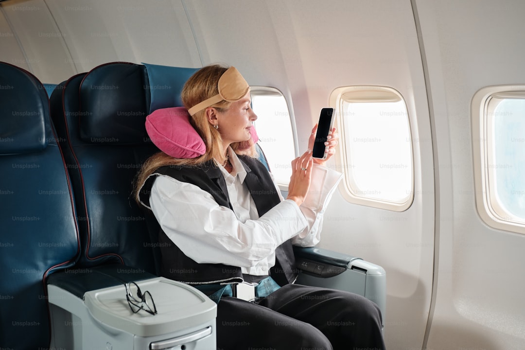 A woman sitting in an airplane holding a cell phone