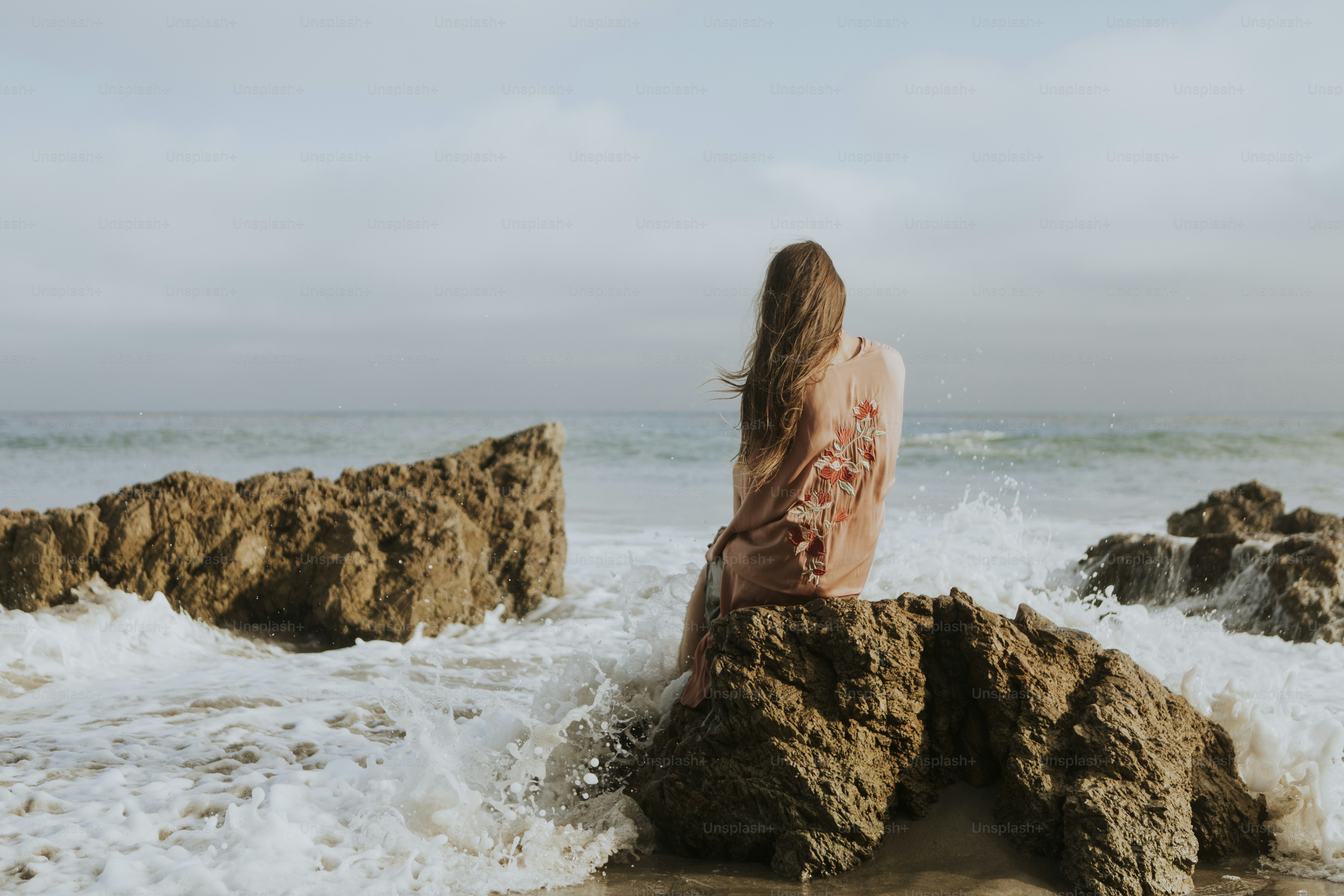 Back of a woman sitting along at the beach