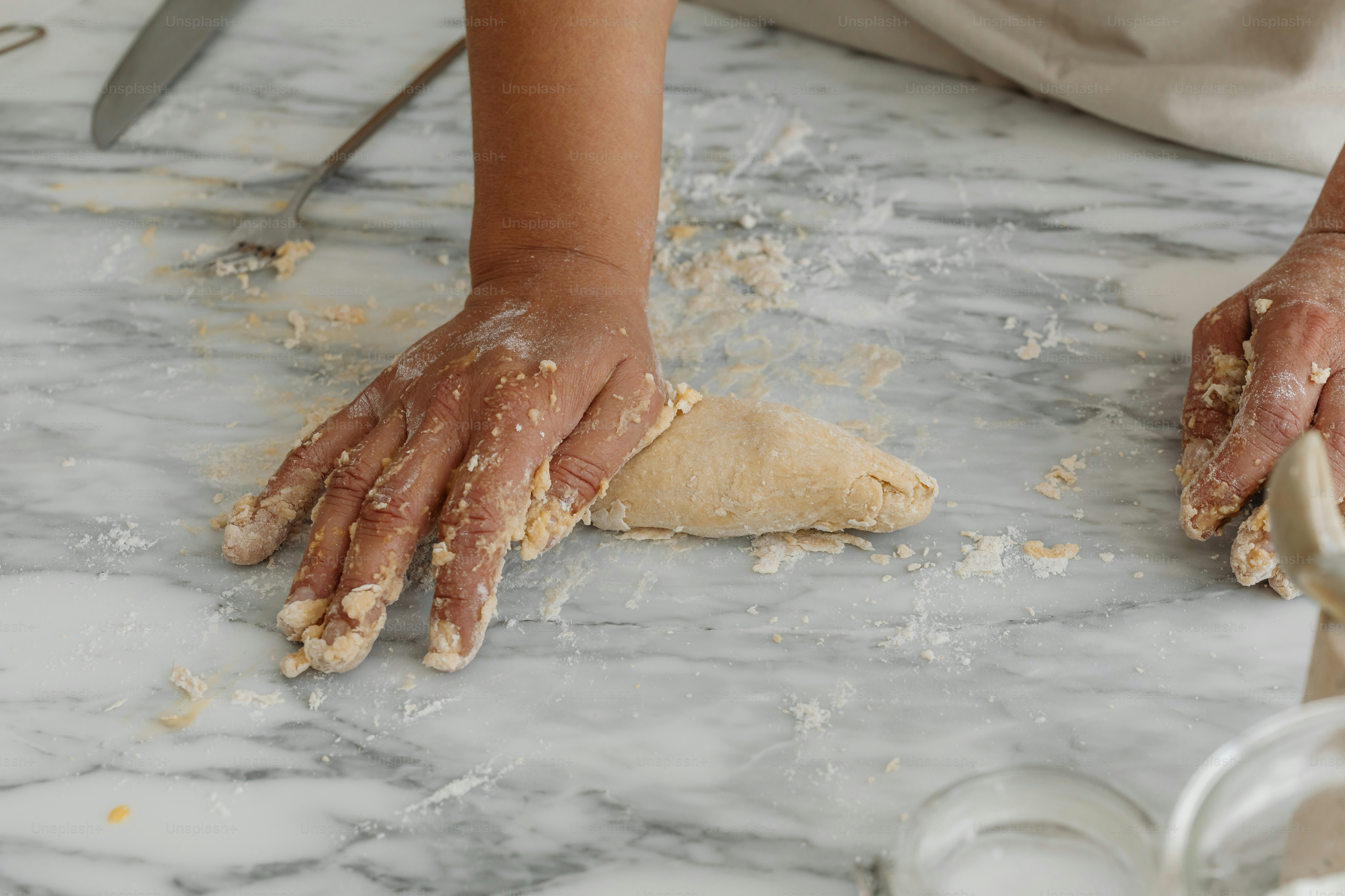 A person kneading dough on top of a counter