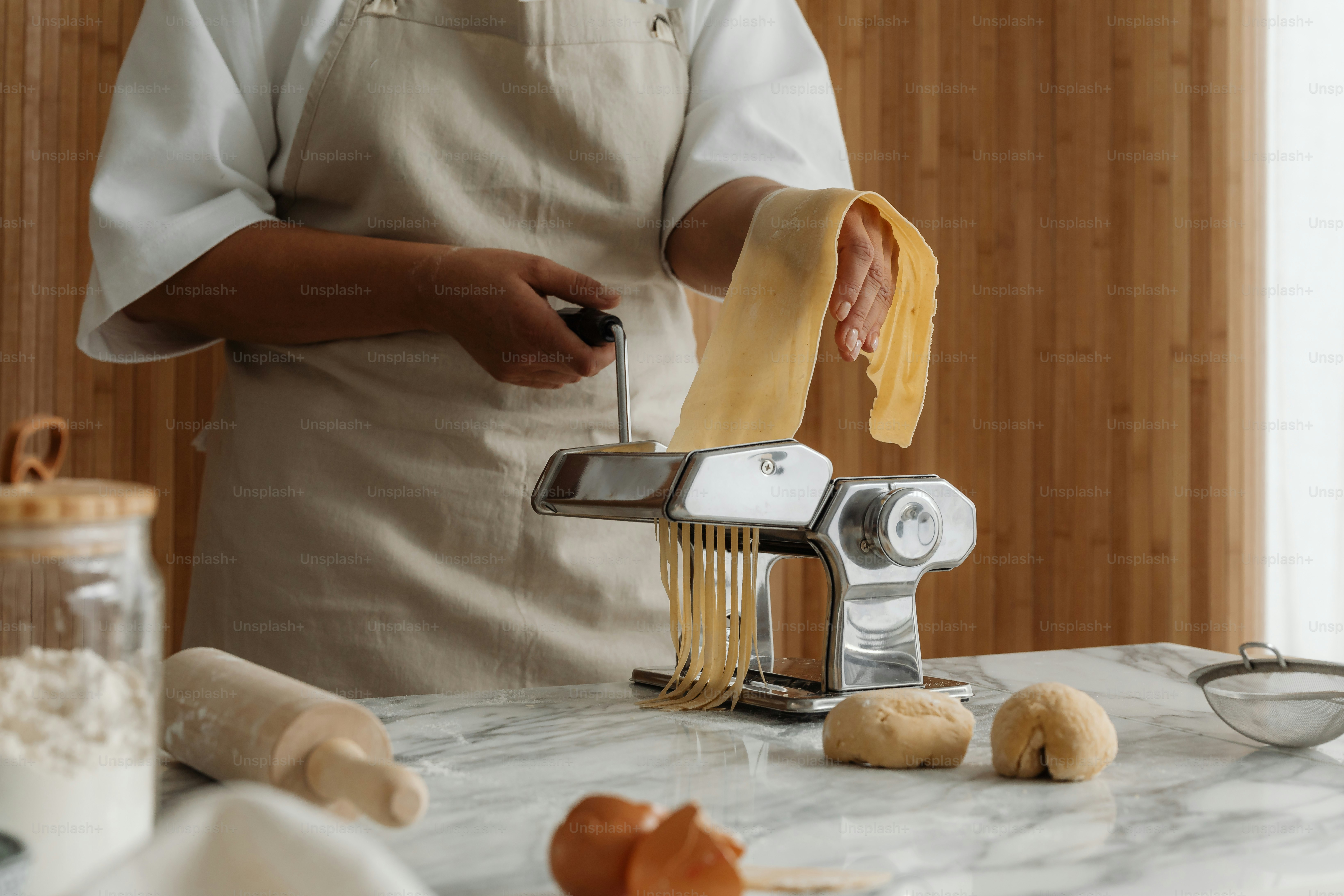 A woman in an apron is making pasta