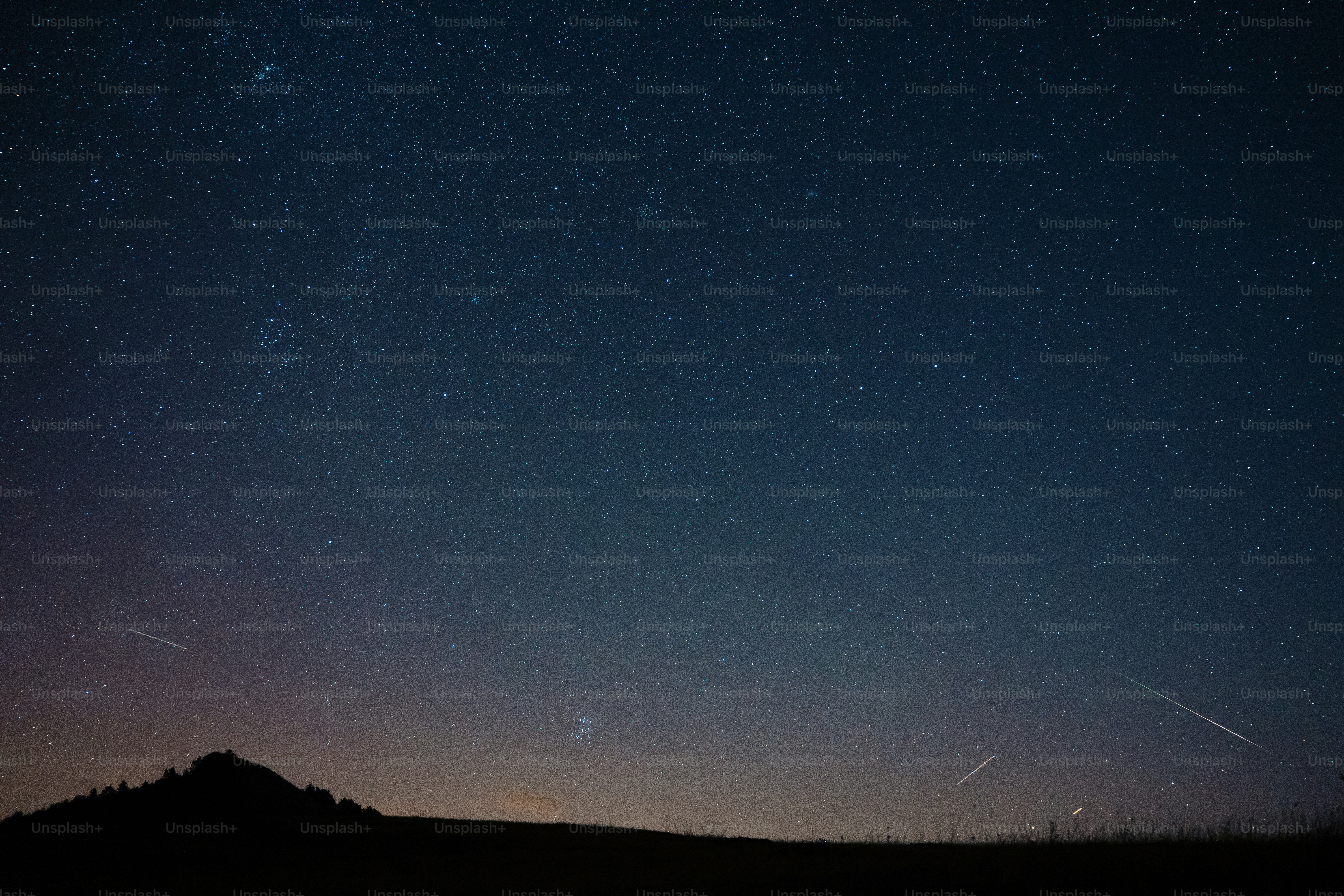 Un ciel nocturne avec des étoiles et une montagne en arrière-plan