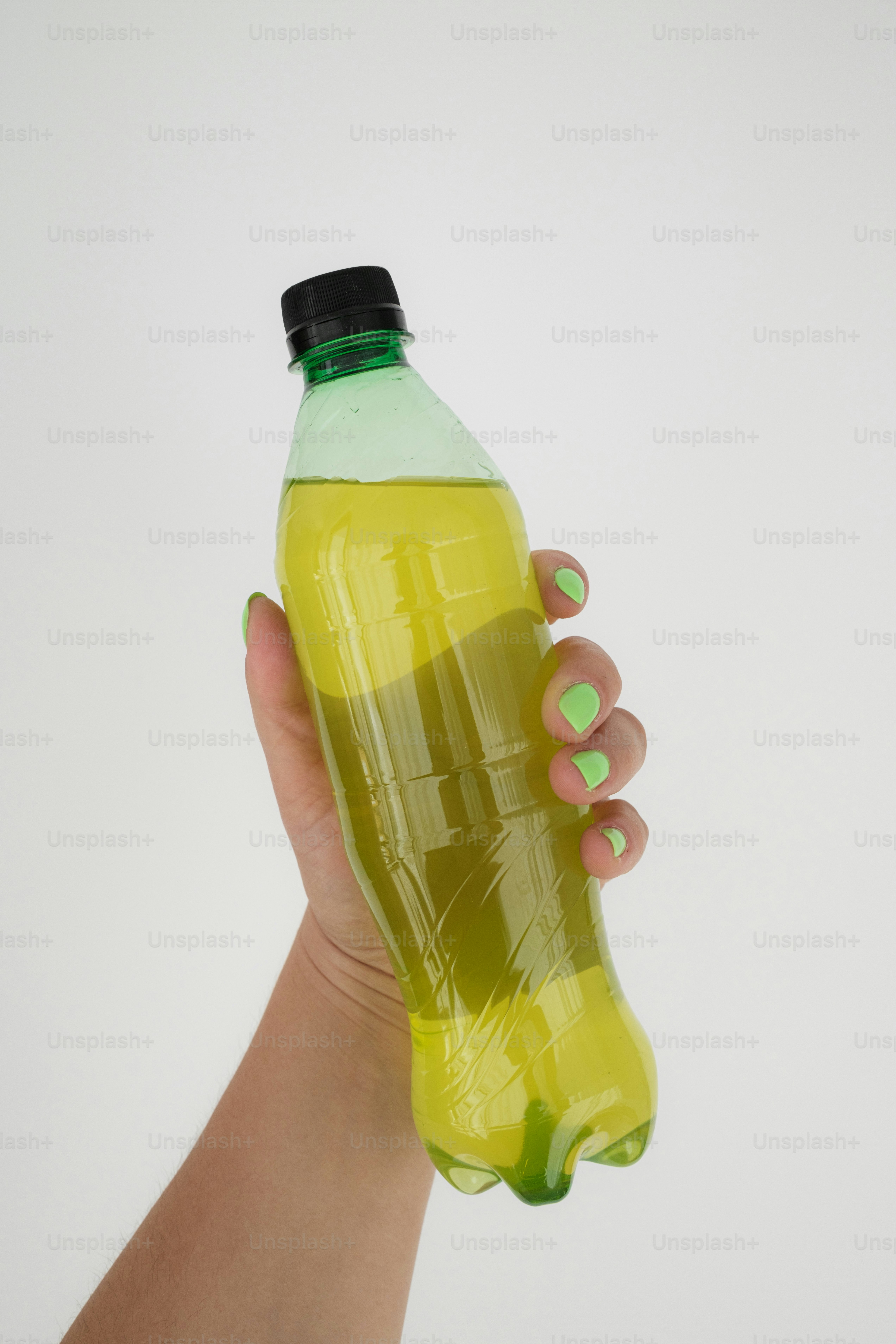 A hand holding a green bottle of liquid