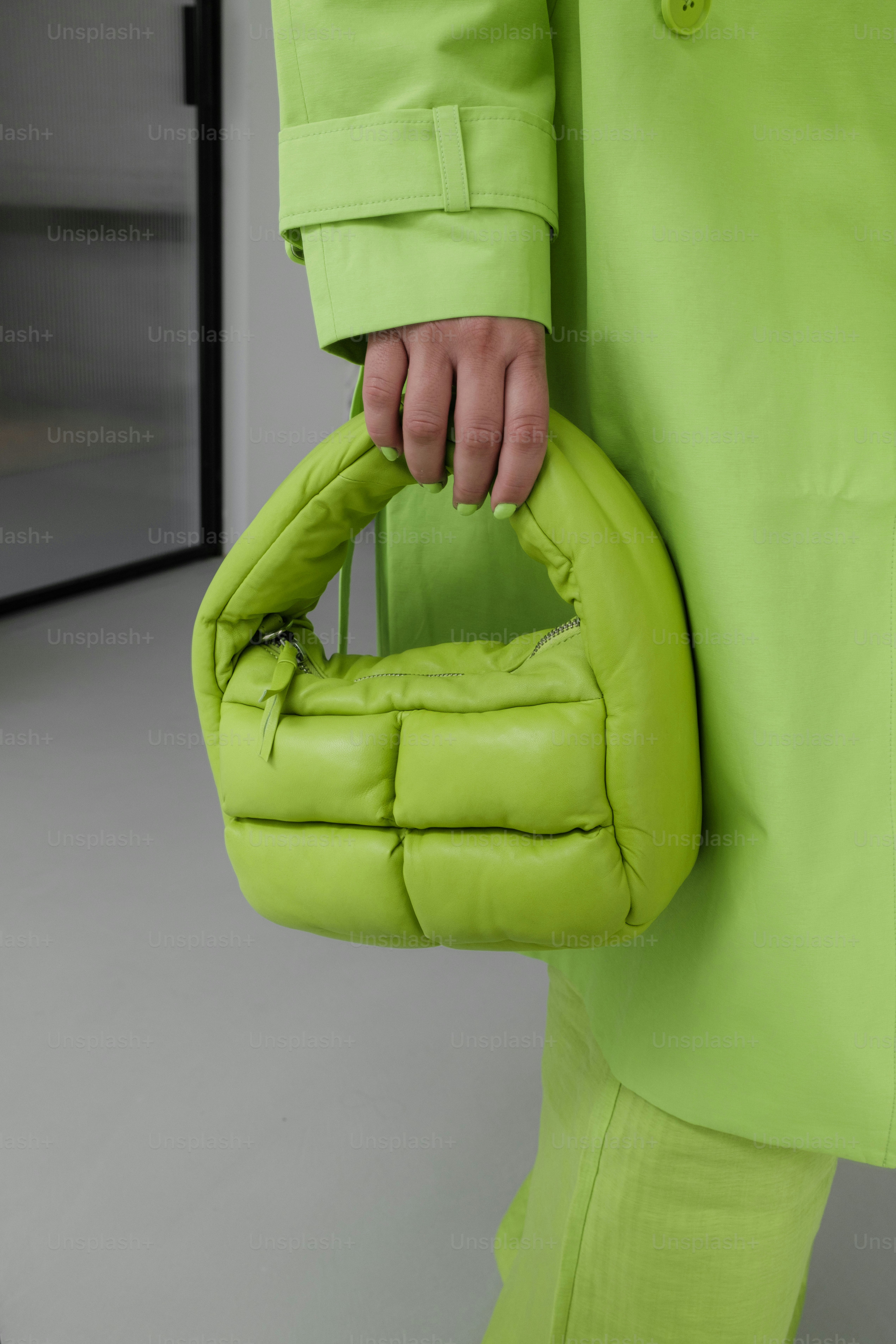 A person in a green coat holding a green bag