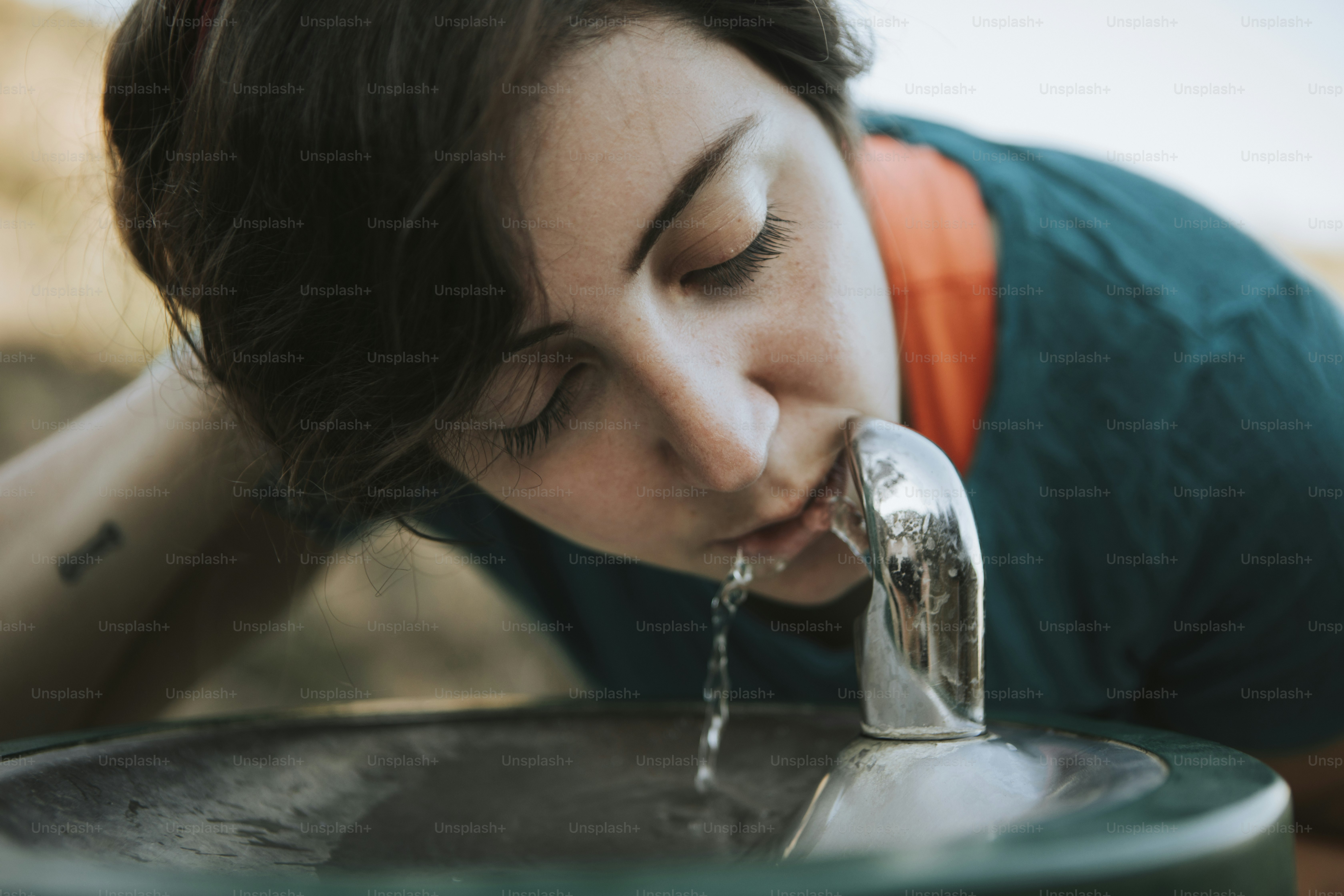 Mulher bebendo água de uma fonte de água