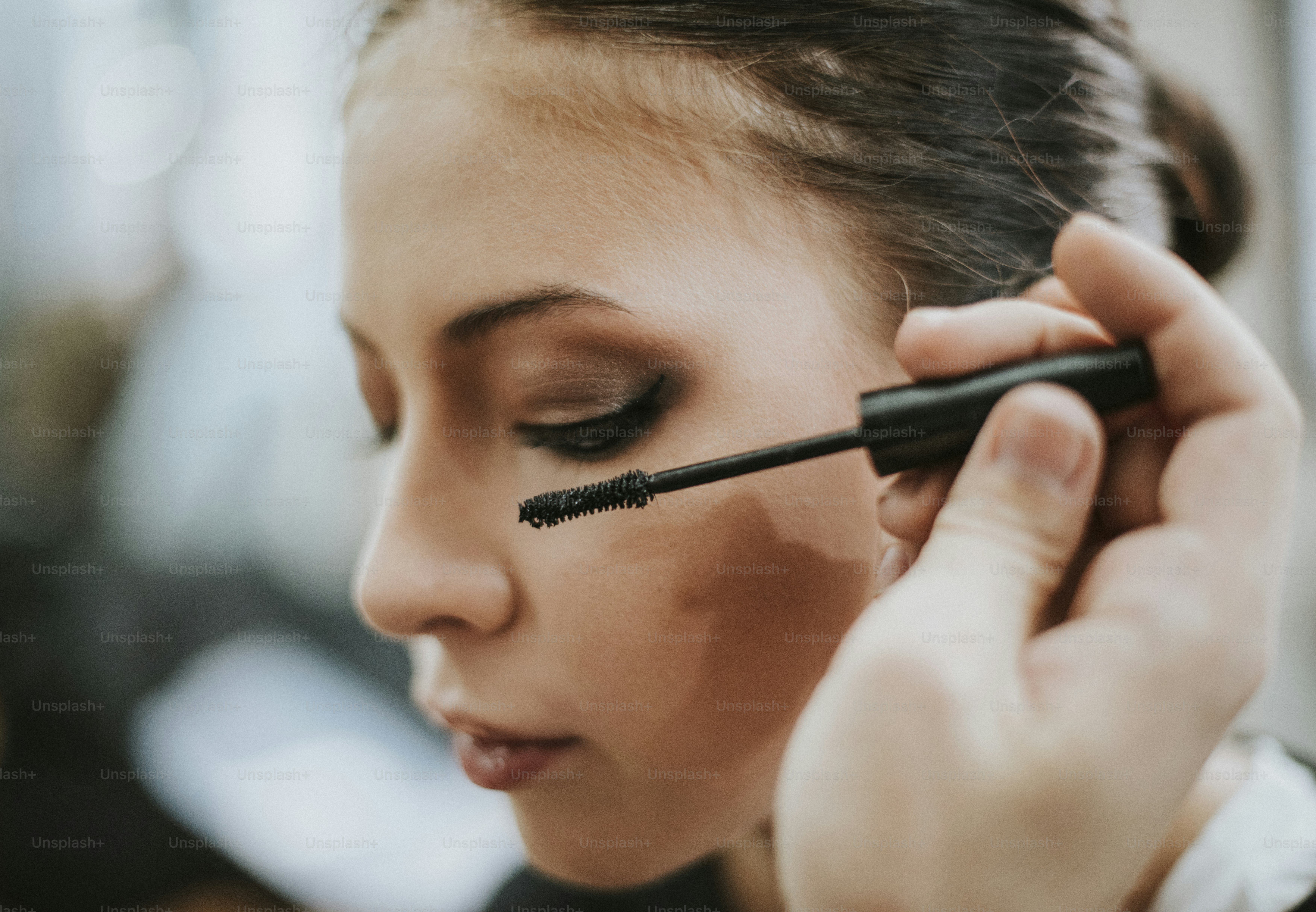 Makeup artist applying mascara onto the model