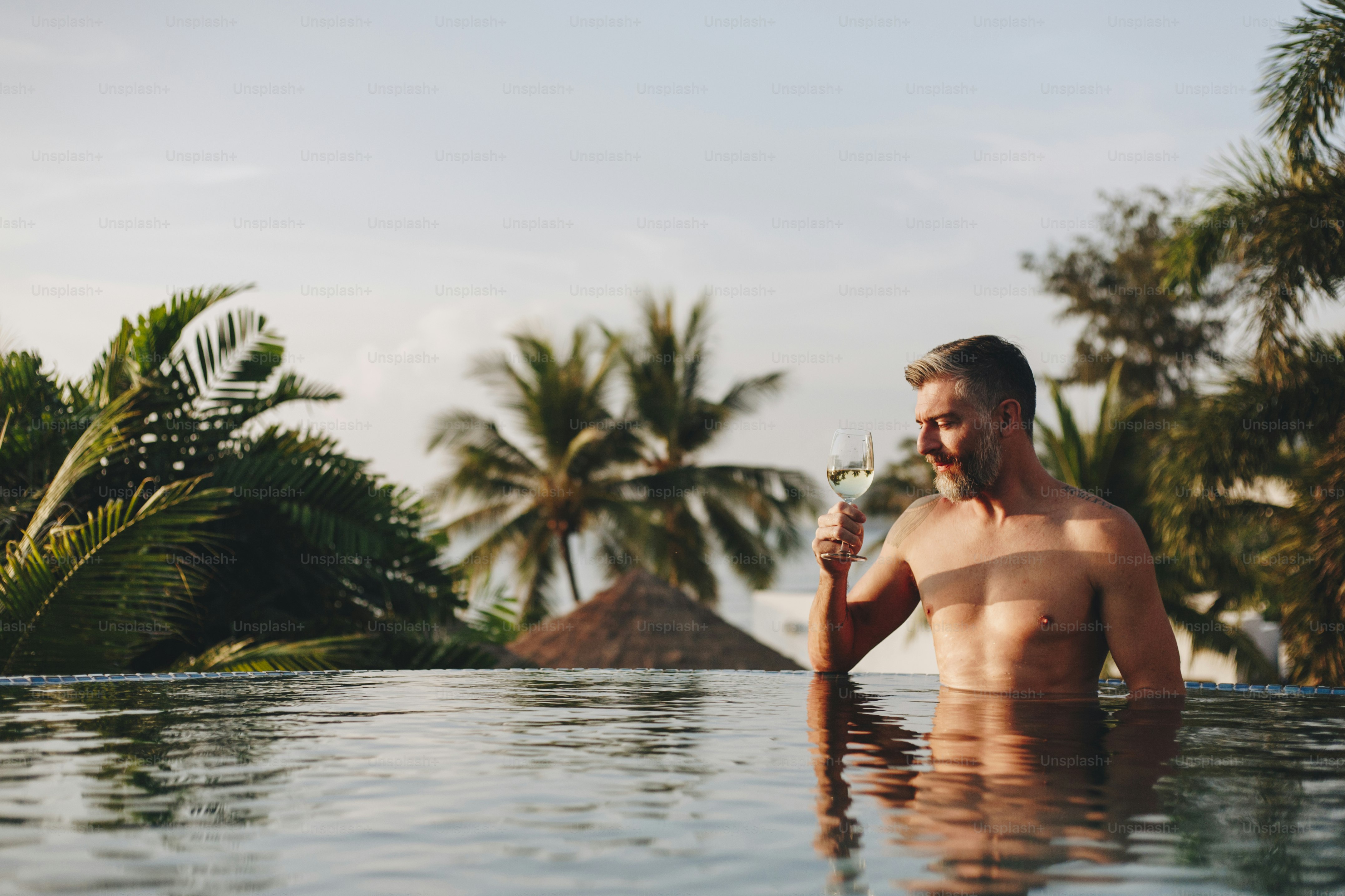 Handsome man having a glass of wine in the pool