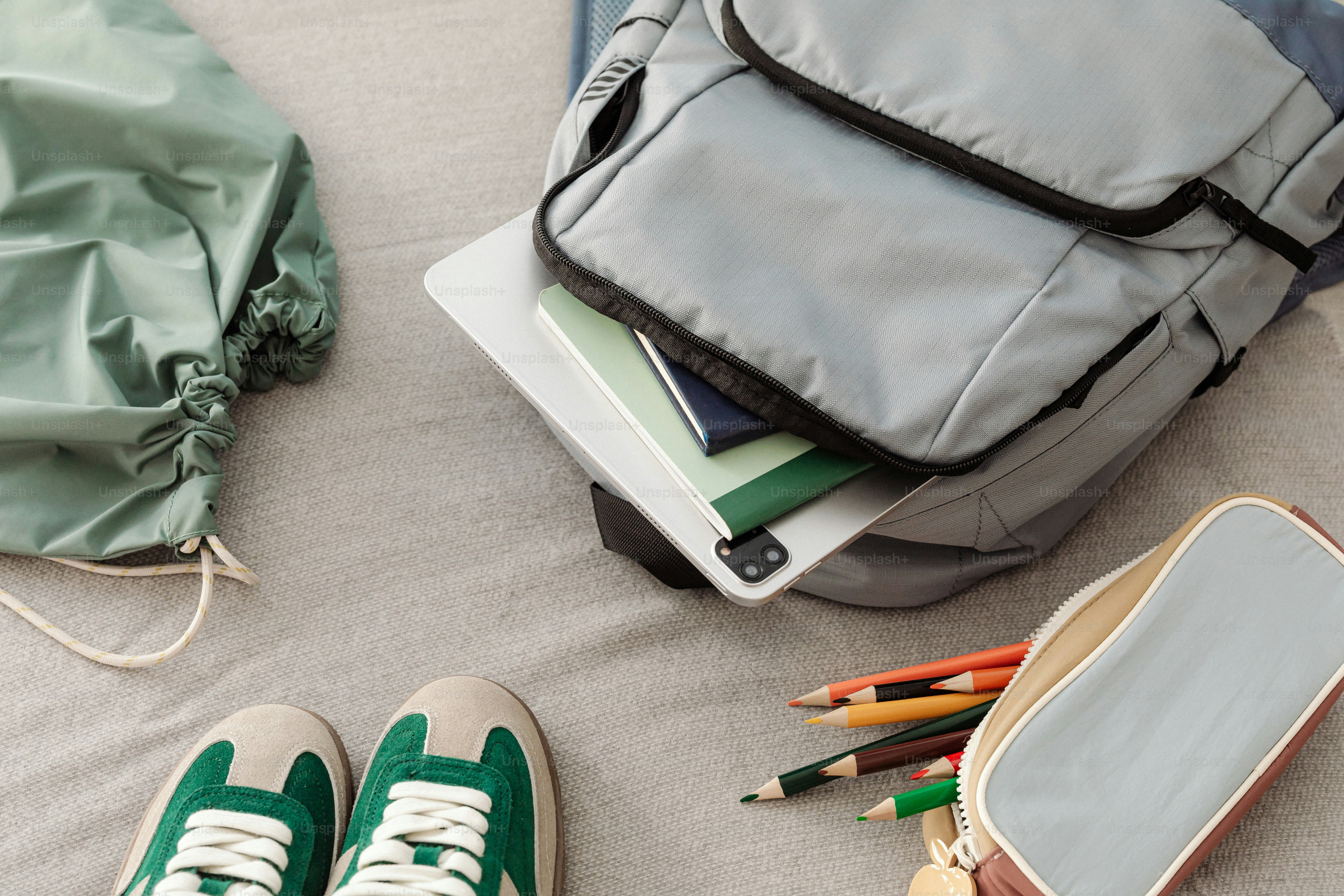 A pair of green tennis shoes sitting on top of a bed next to a backpack