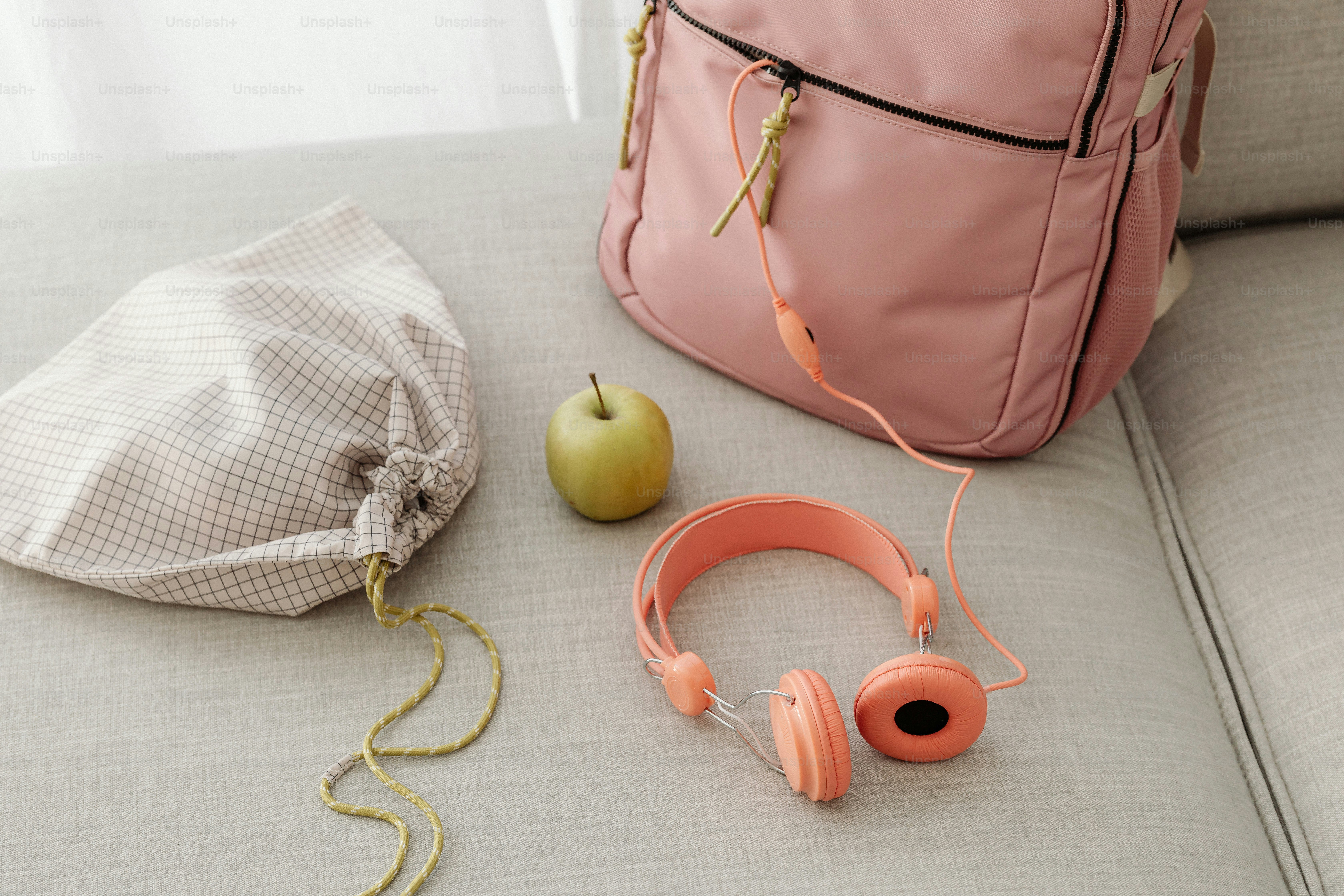 A backpack, headphones, and an apple on a couch