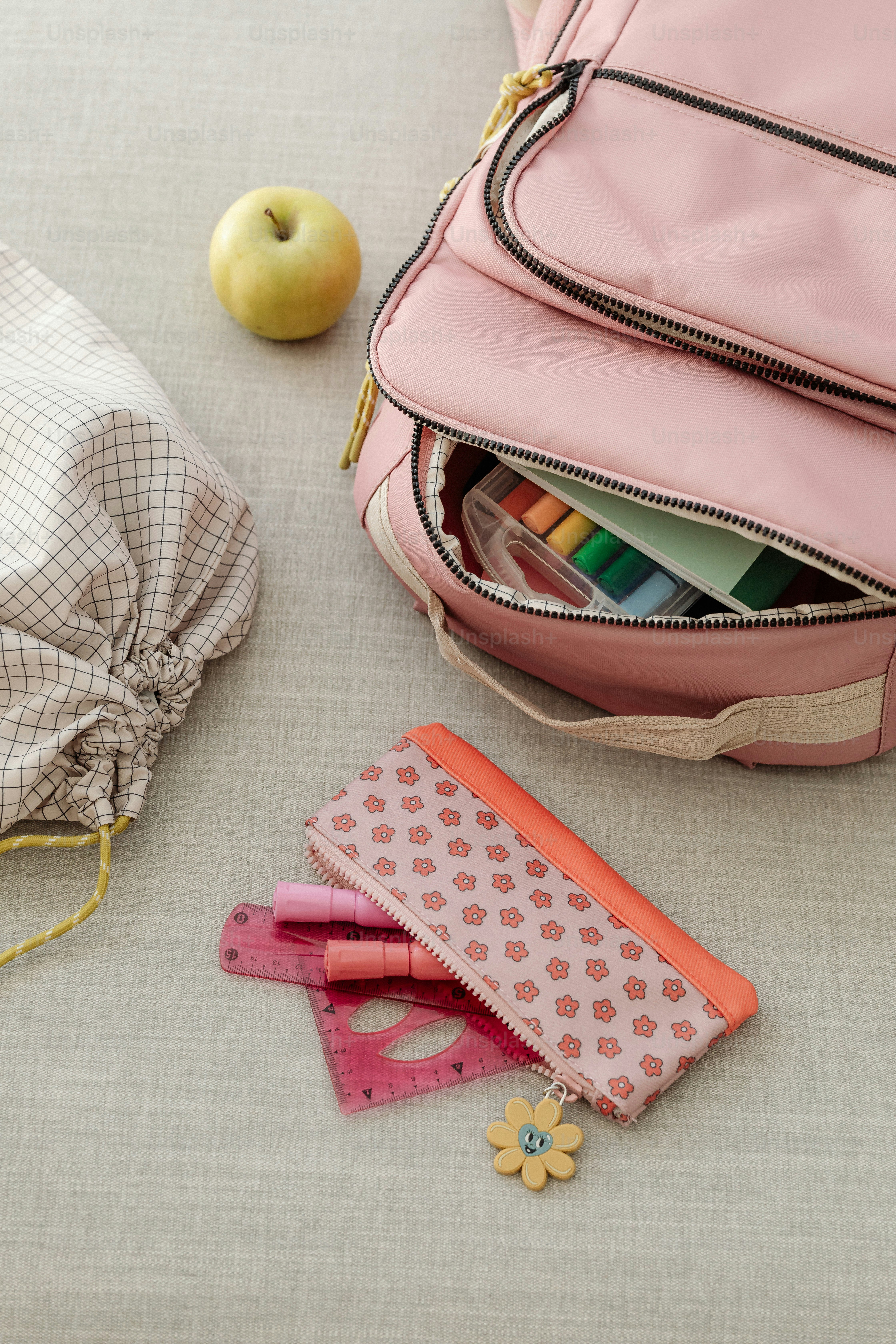 Ein rosafarbener Rucksack und ein paar Schulsachen auf einem Tisch