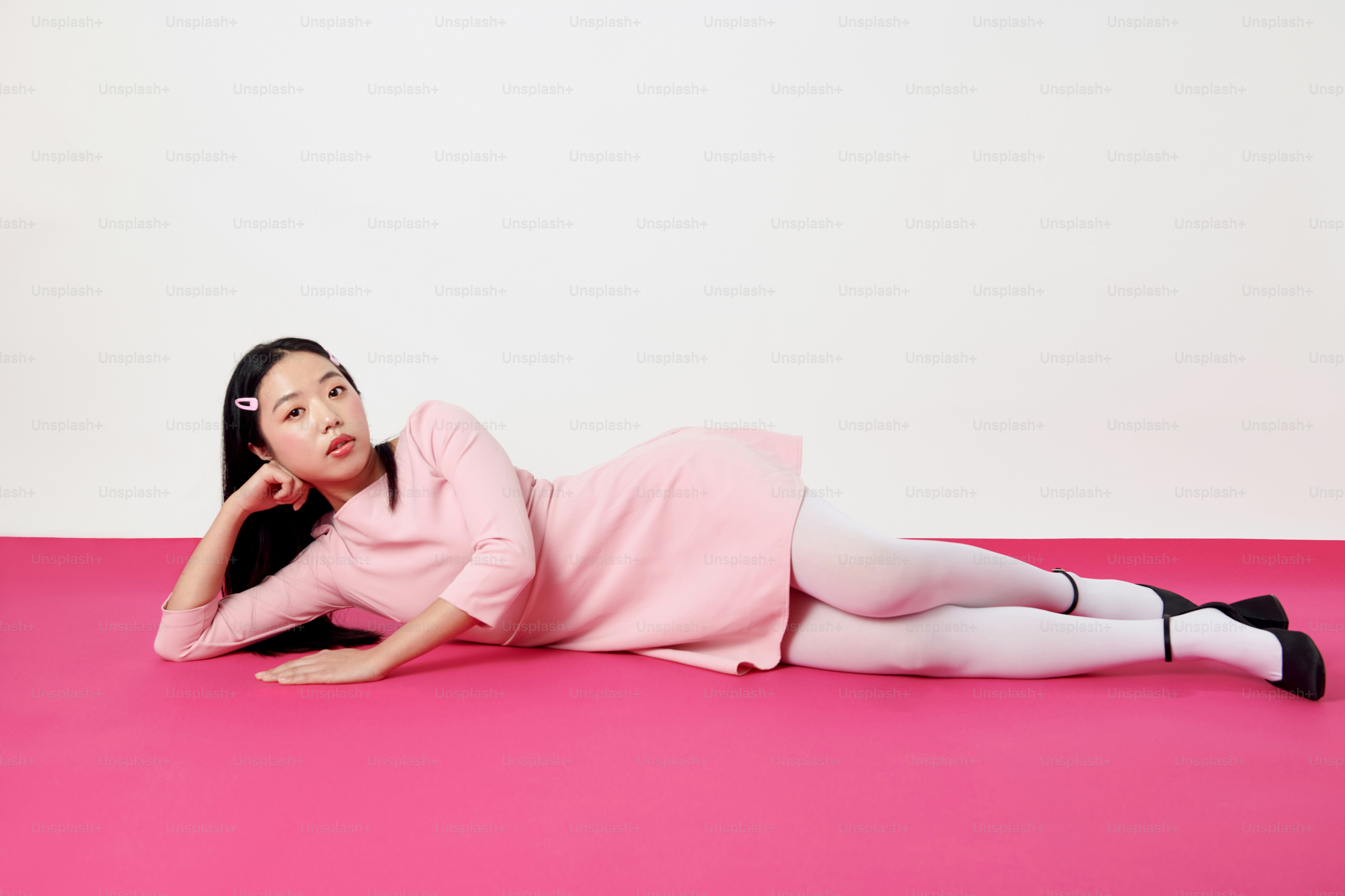 A woman in a pink dress laying on a pink floor