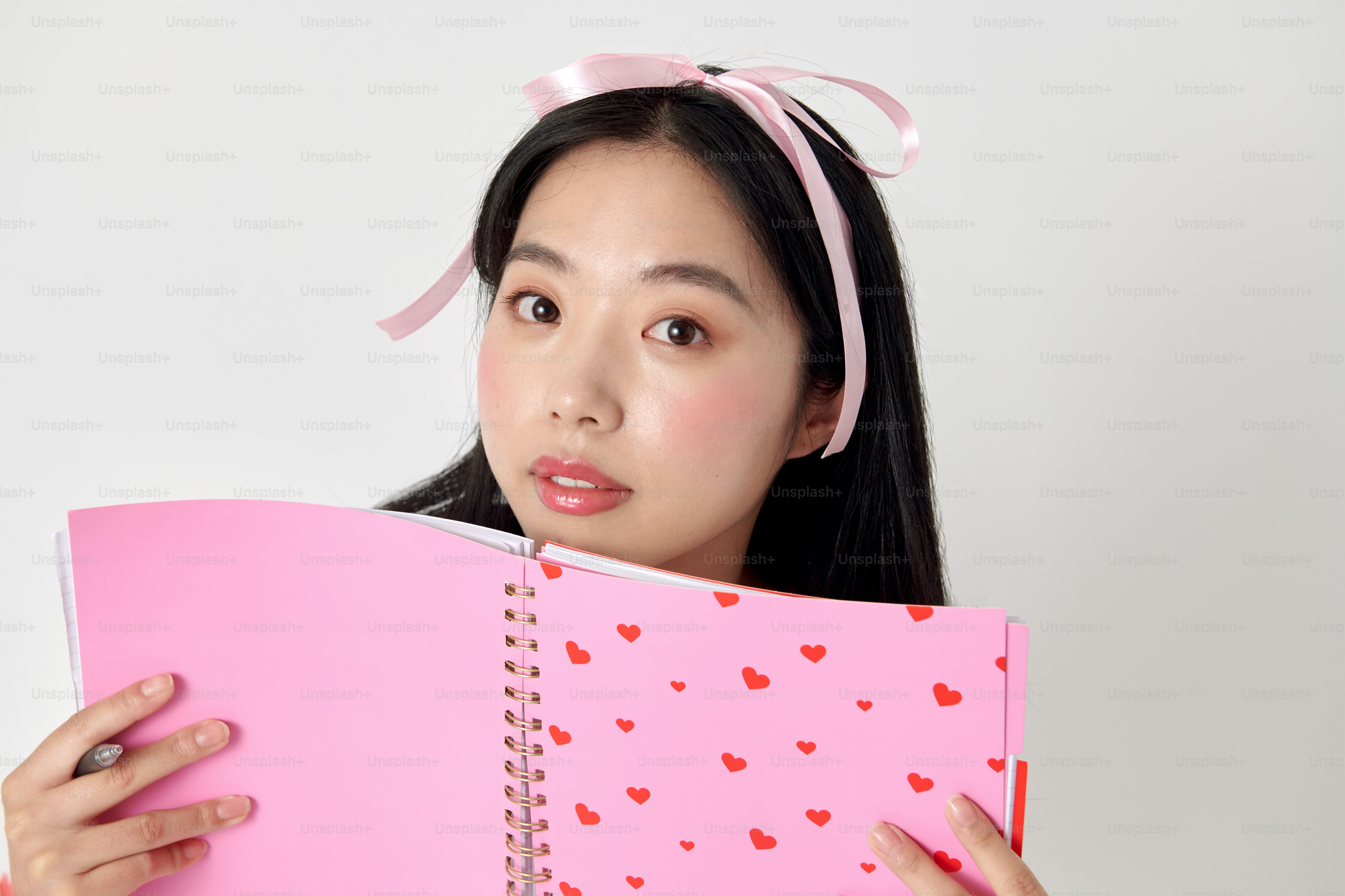 A woman holding a pink notebook with hearts on it