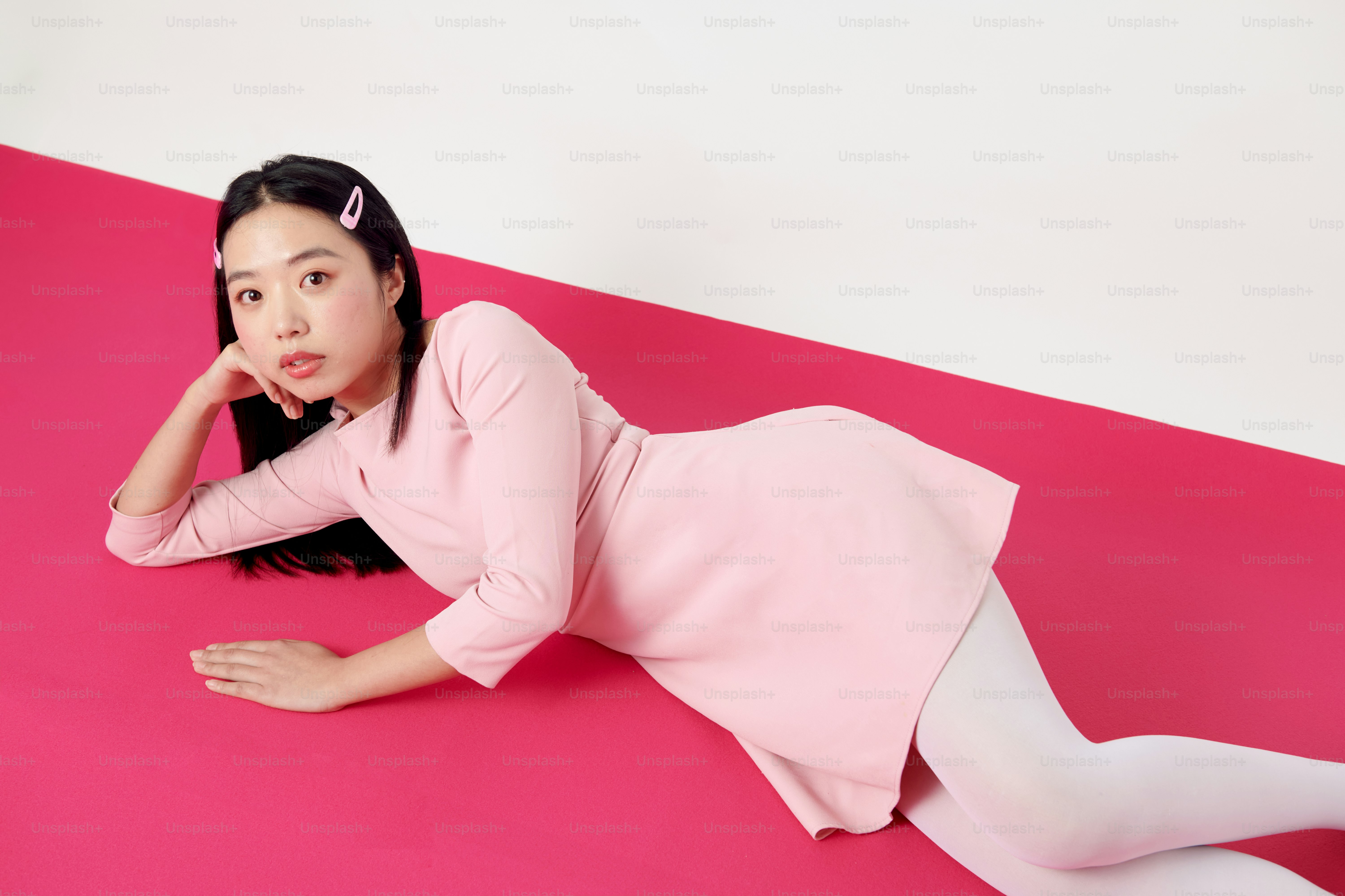 ピンクの床に横たわるピンクのドレスを着た女性